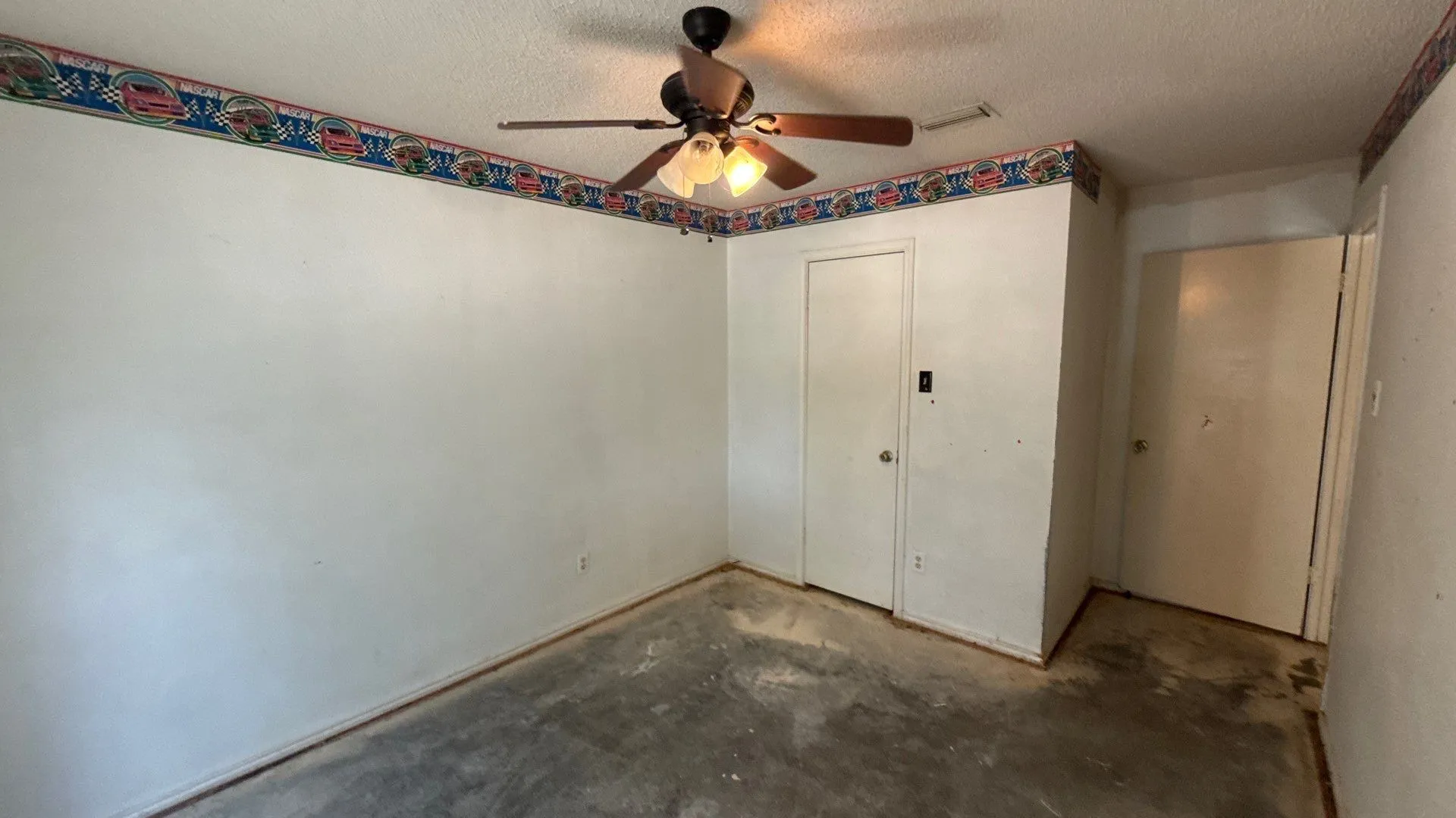 Ceiling fan with light fixture, white walls, and two white doors