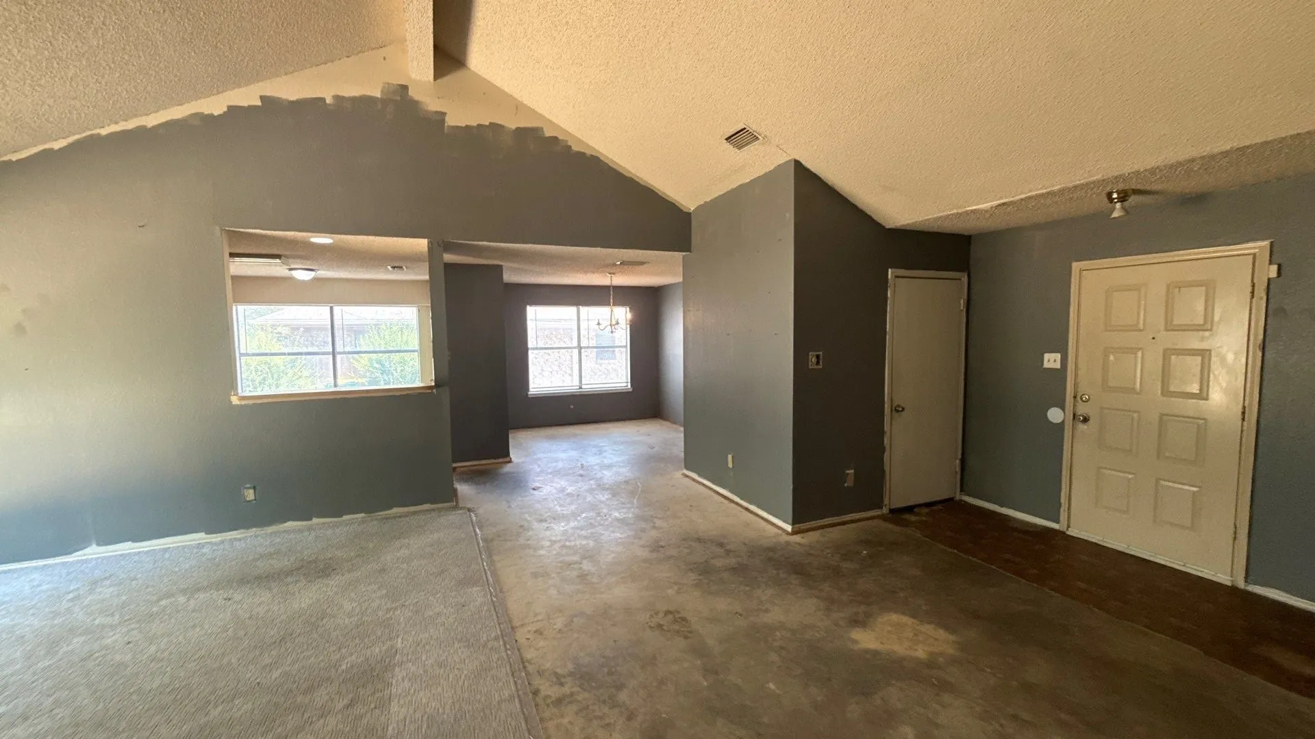 Vaulted ceiling, interior wall cutout, multiple windows, recessed lighting, paneled entry door