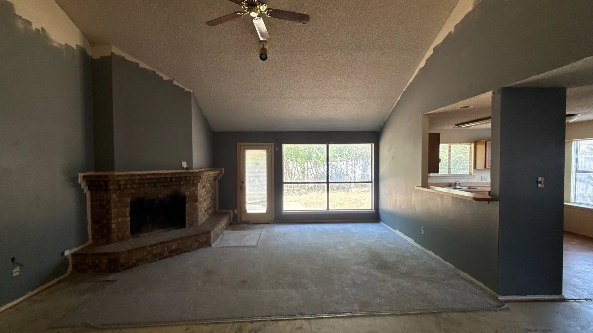 Brick-clad fireplace feature, large window, and a pass-through opening with a wood-finish countertop