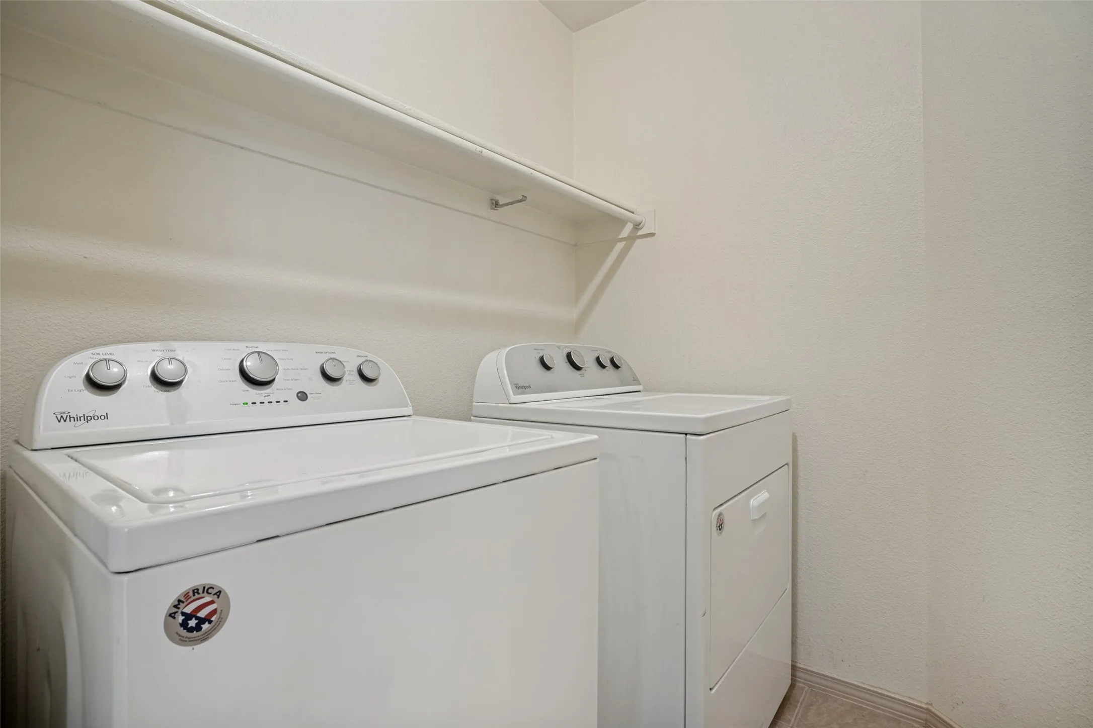White washer and dryer units with a wall-mounted shelf