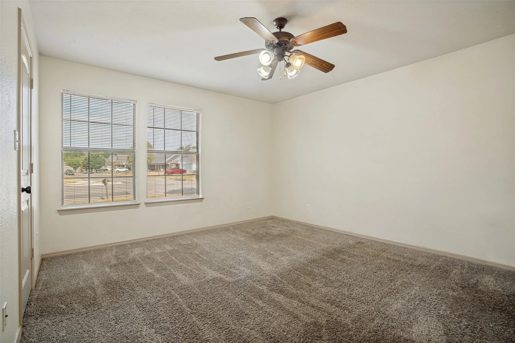 Vaulted ceiling with a ceiling fan, two windows featuring blinds, and neutral-toned carpeting