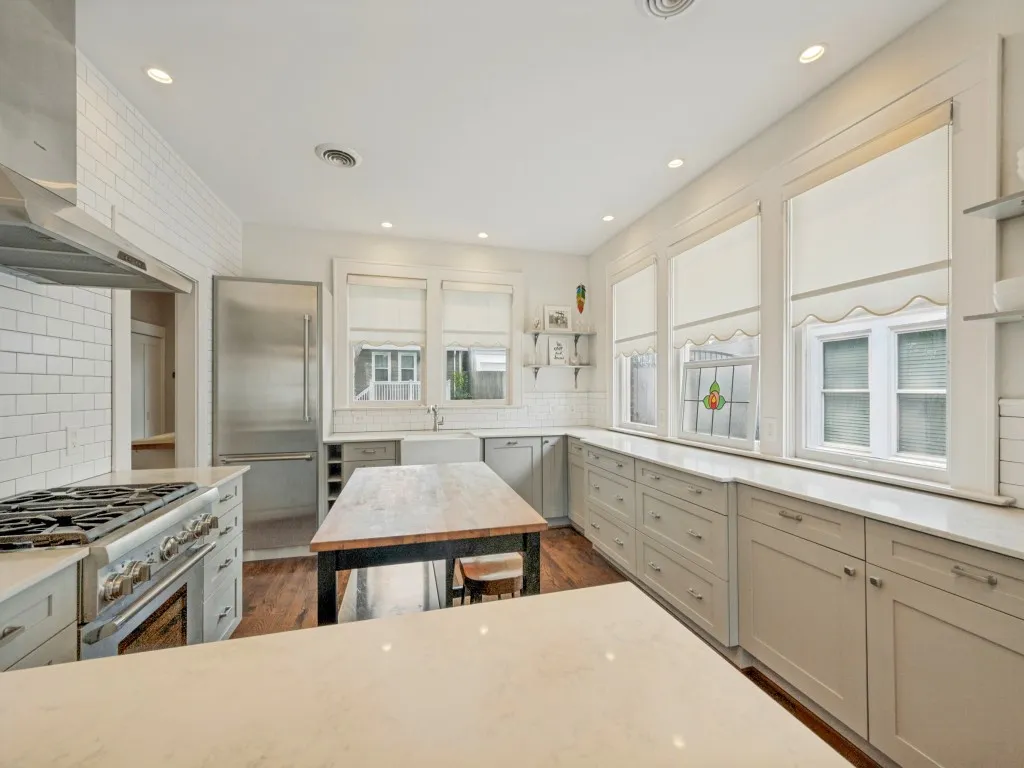 Gourmet kitchen featuring a stainless steel range, built-in refrigerator, subway tile backsplash, recessed lighting, and a wood-top island with integrated storage