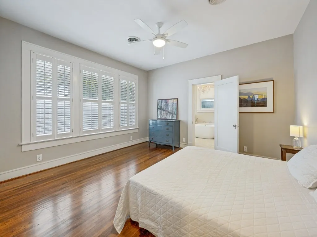 Wood flooring, white plantation shutters, ceiling fan, and white trim molding