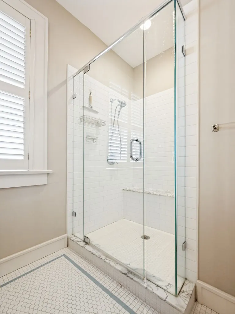 Glass-enclosed shower with white subway tile, a built-in bench, and a hexagonal floor tile pattern