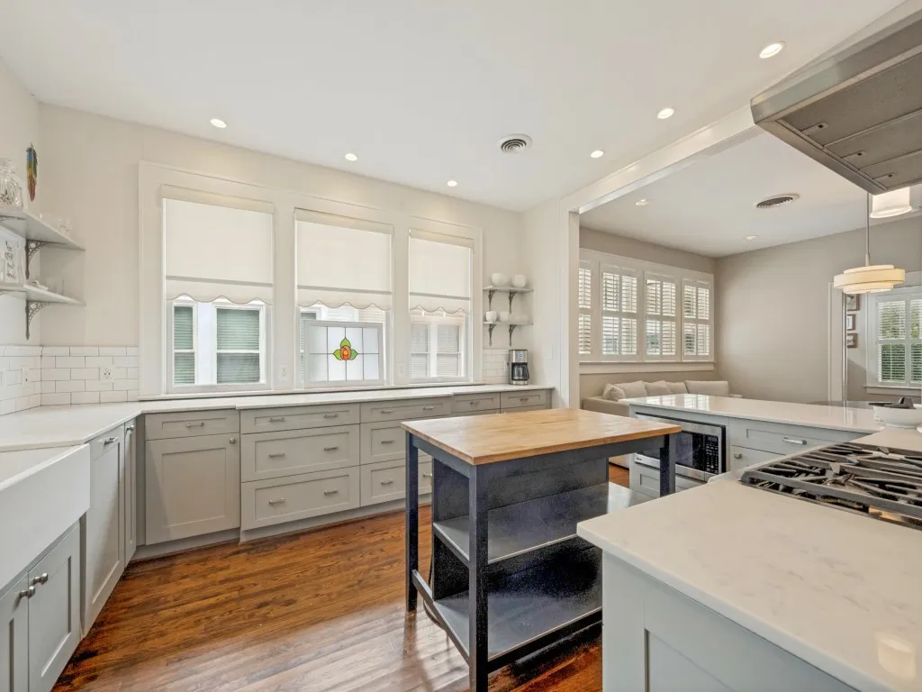 Kitchen featuring wood-finish flooring, recessed lighting, light-toned cabinetry, light countertops, and a built-in range hood
