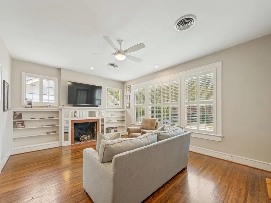 Hardwood flooring, recessed lighting, ceiling fan, fireplace with mantel, and built-in shelving