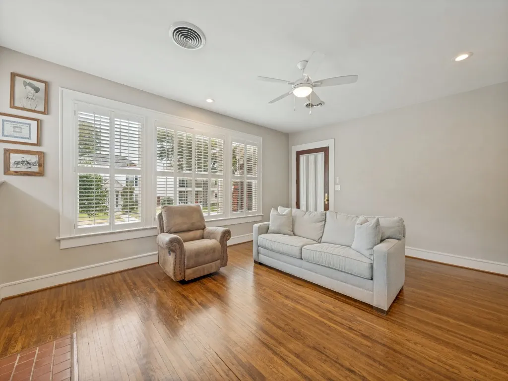 Hardwood flooring, multiple windows with plantation shutters, ceiling fan, recessed lighting, and a paneled door
