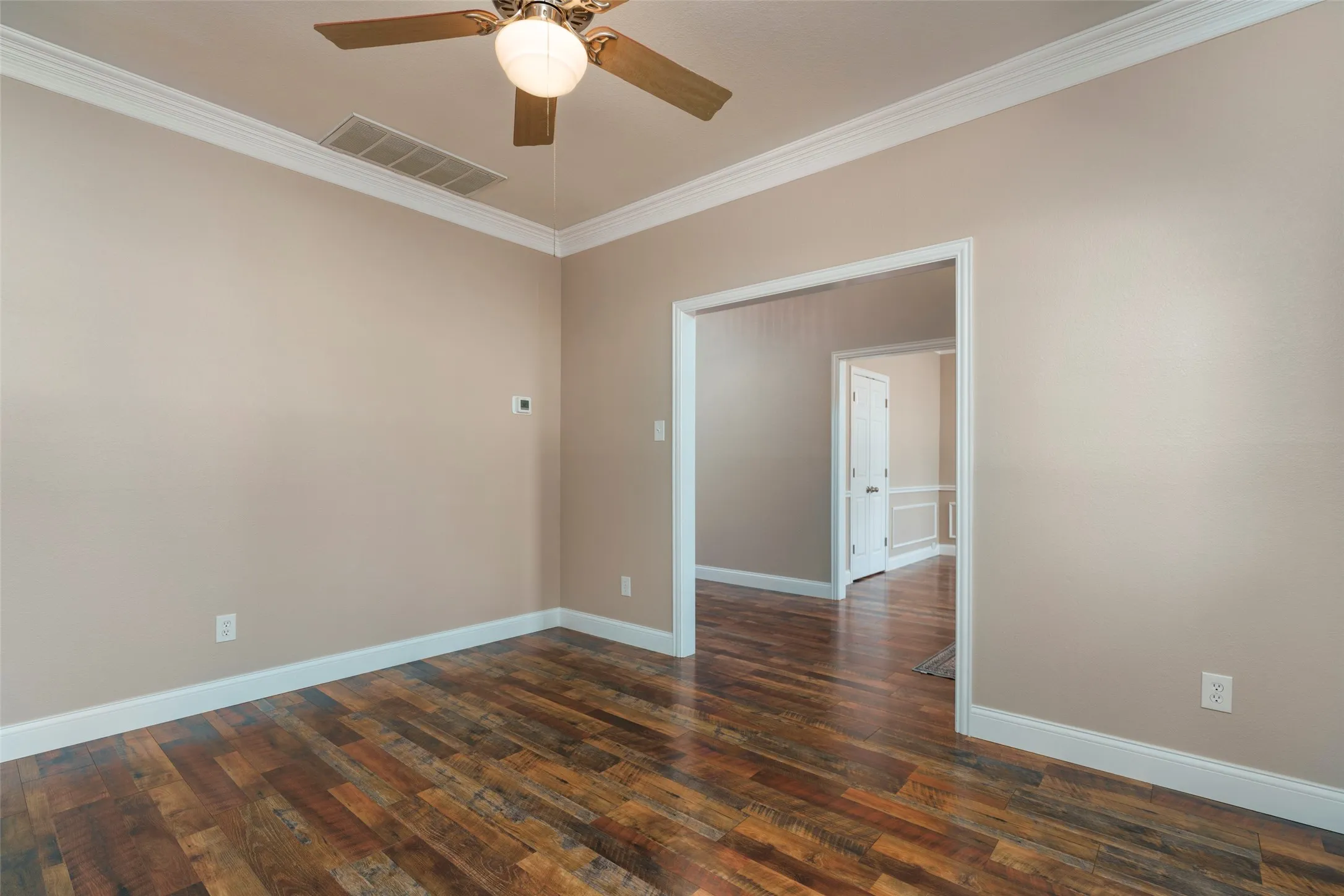 Wood-finish flooring with crown molding and a ceiling fan