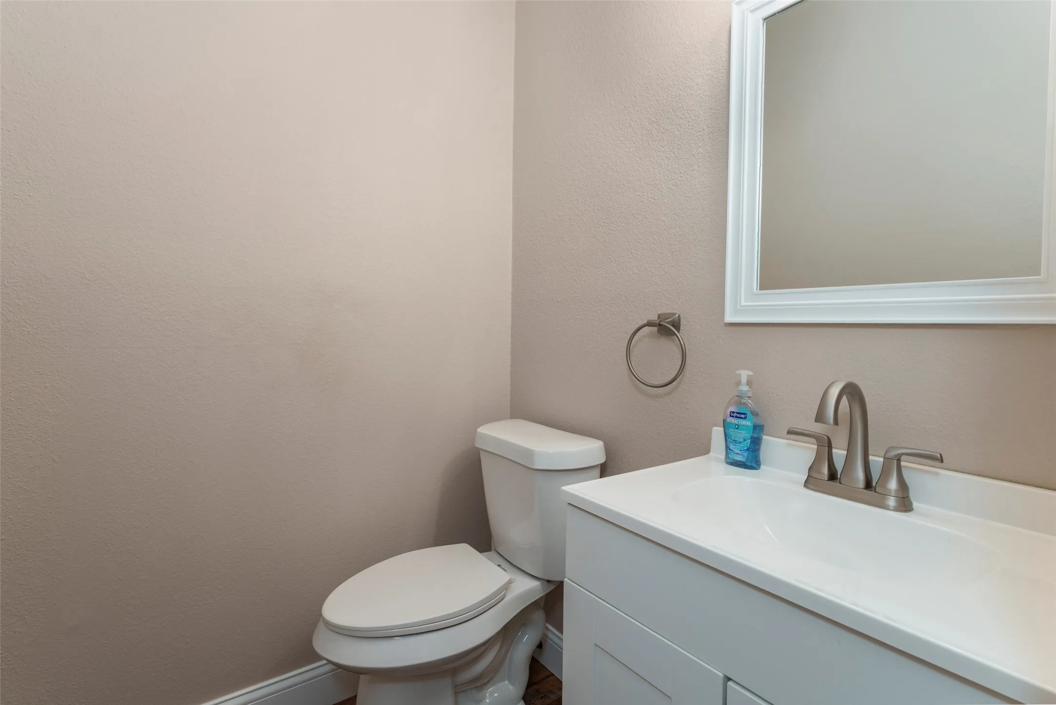 White vanity with integrated sink, brushed nickel faucet, and framed wall mirror