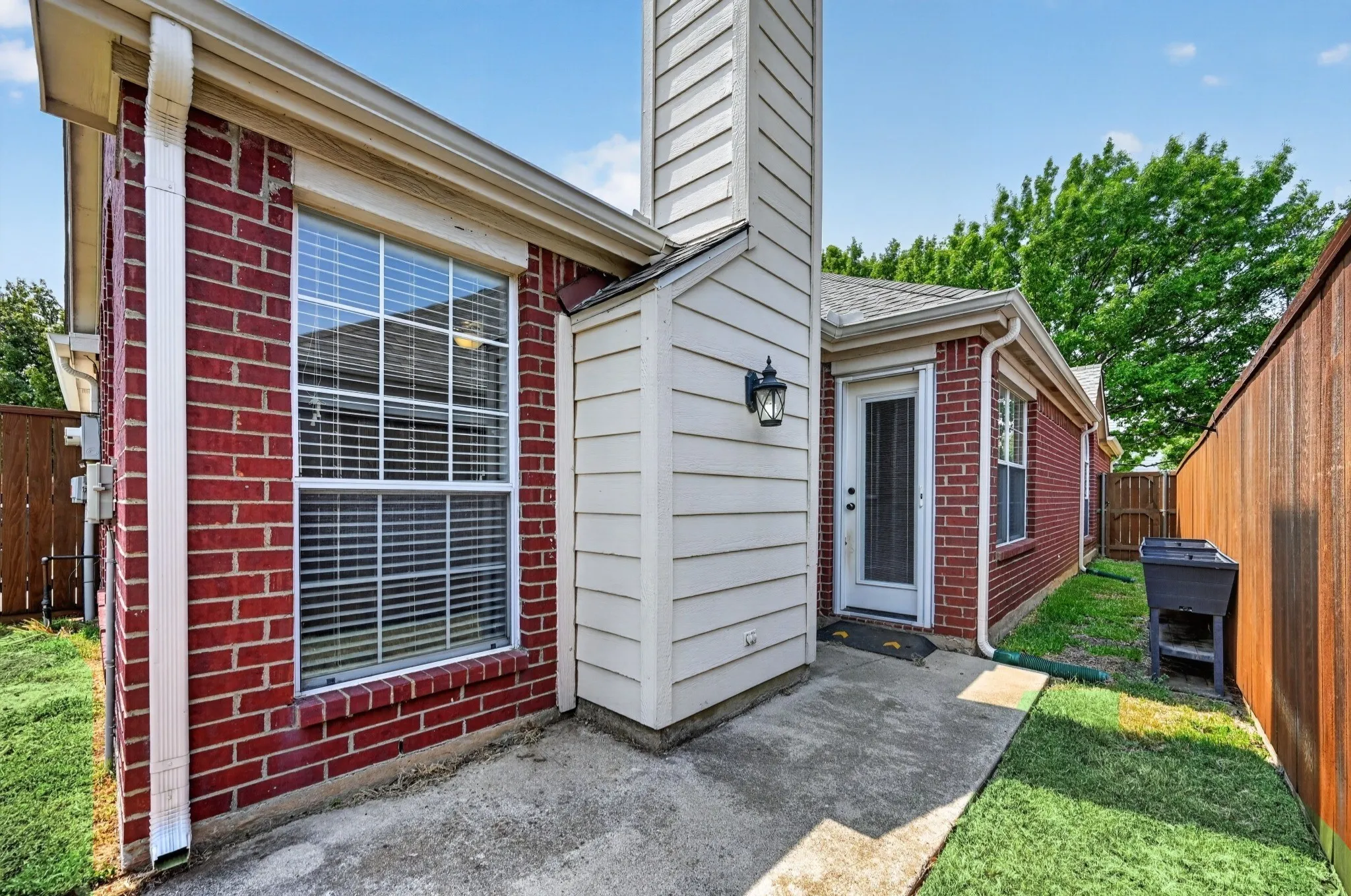 Brick exterior with white trim, a fixed window with blinds, and a white storm door