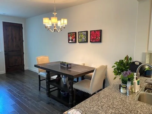 Wood-finish flooring, dark wood-finish interior door, five-light chandelier, and granite-style countertops