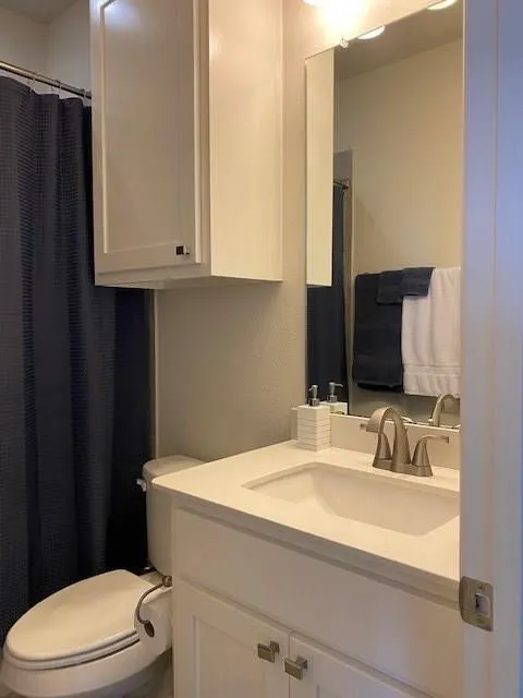 White vanity with brushed nickel hardware, integrated sink, and a single-handle faucet