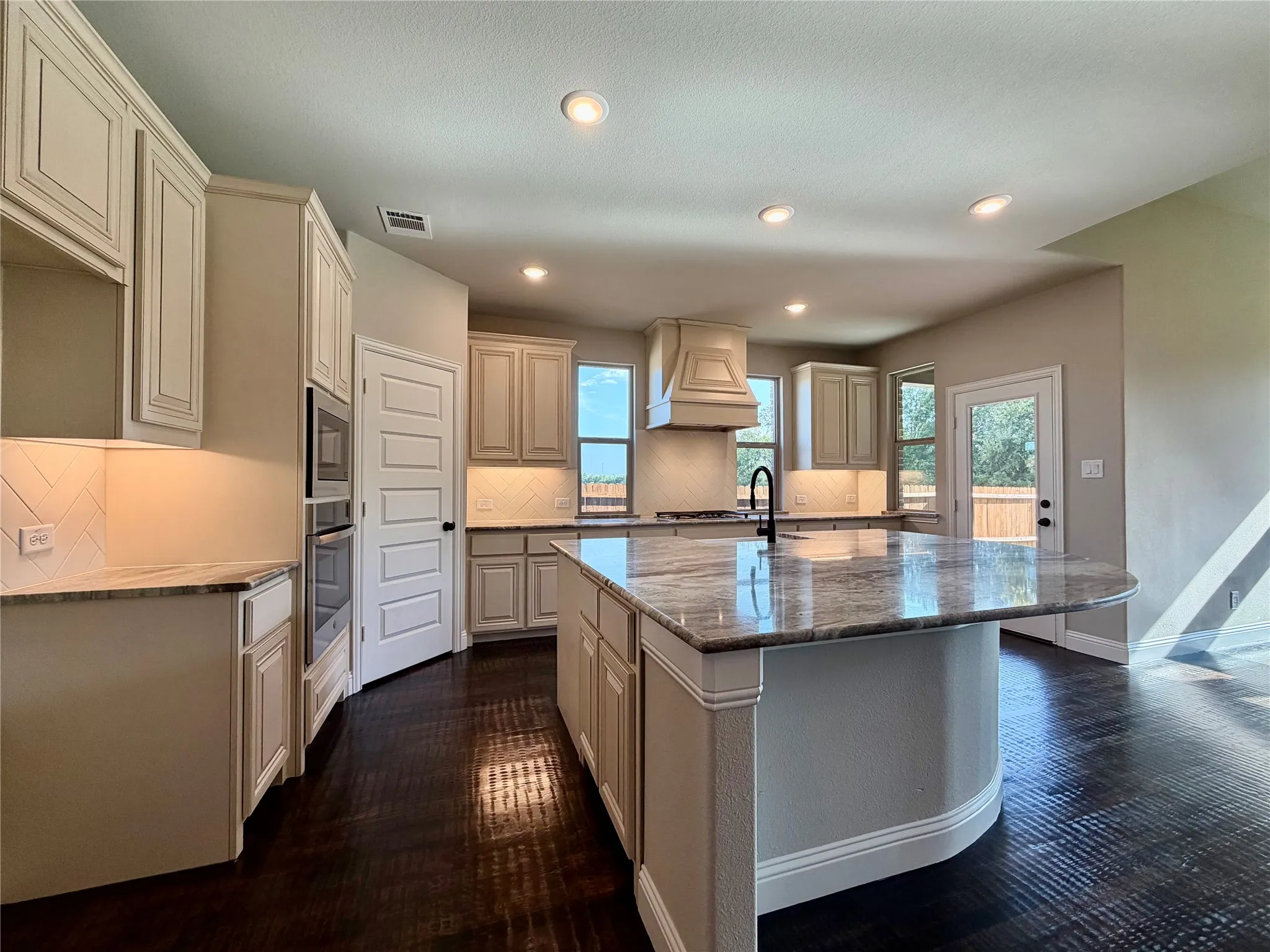 Kitchen offers windows for natural light, stainless built-in appliances, gas cooktop, custom cabinet vent outside, and so much more!