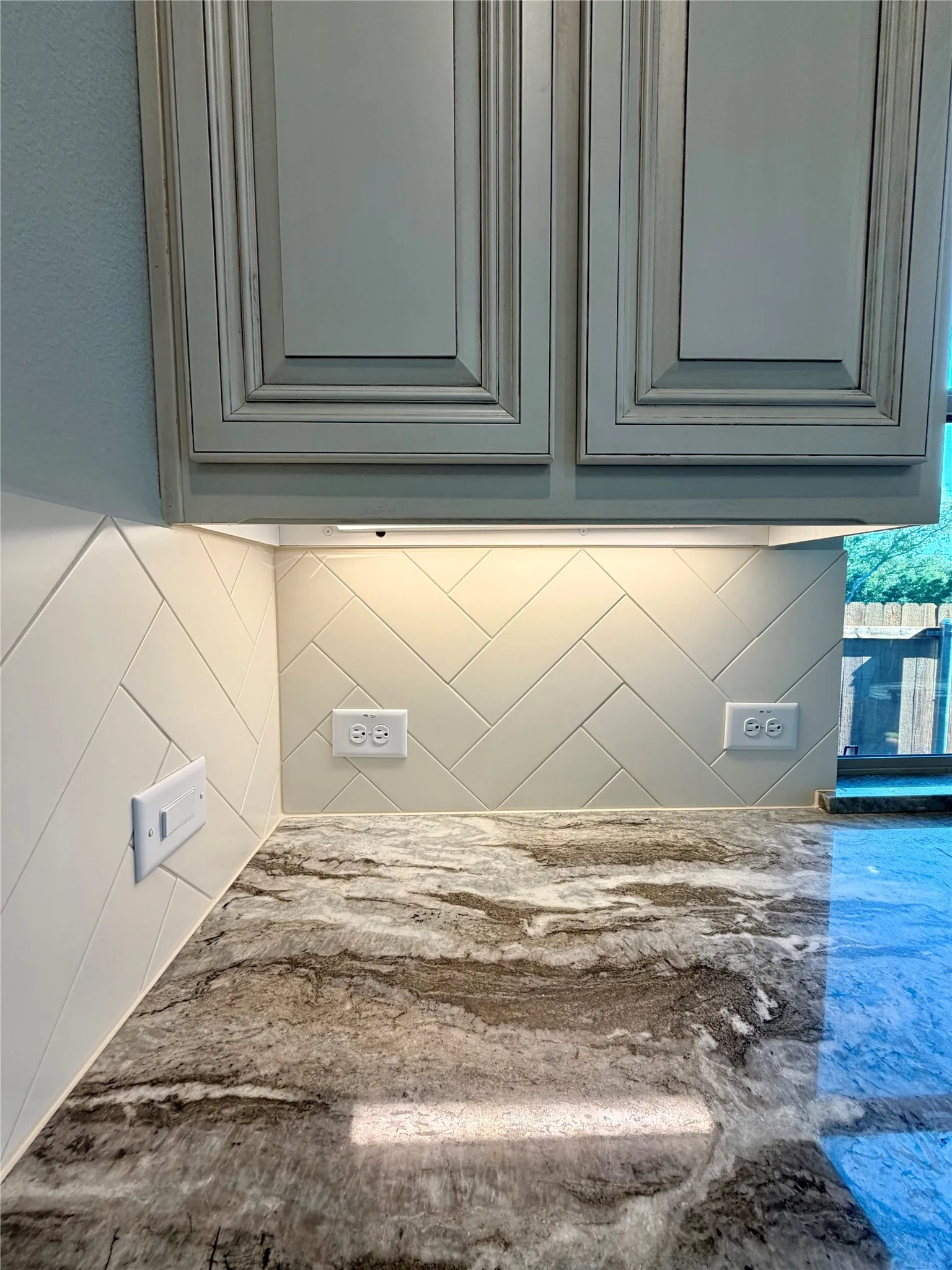 Close up of Soji White cabinets, cream subway tiles in herringbone pattern, and gorgeous Fantasy Brown granite!
