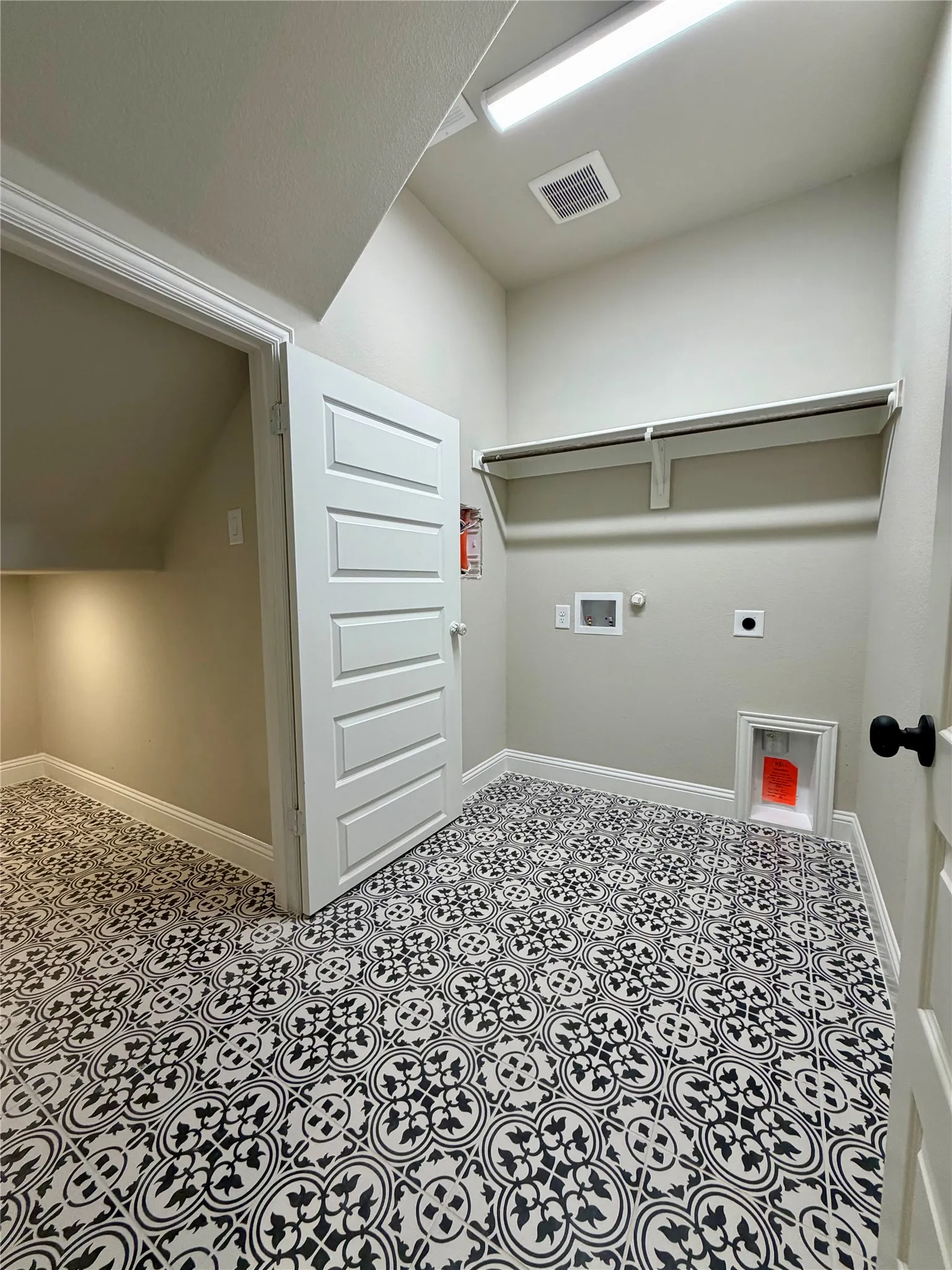 Laudry room is separate with fun decorative tile and it's own storage area under the stairs
