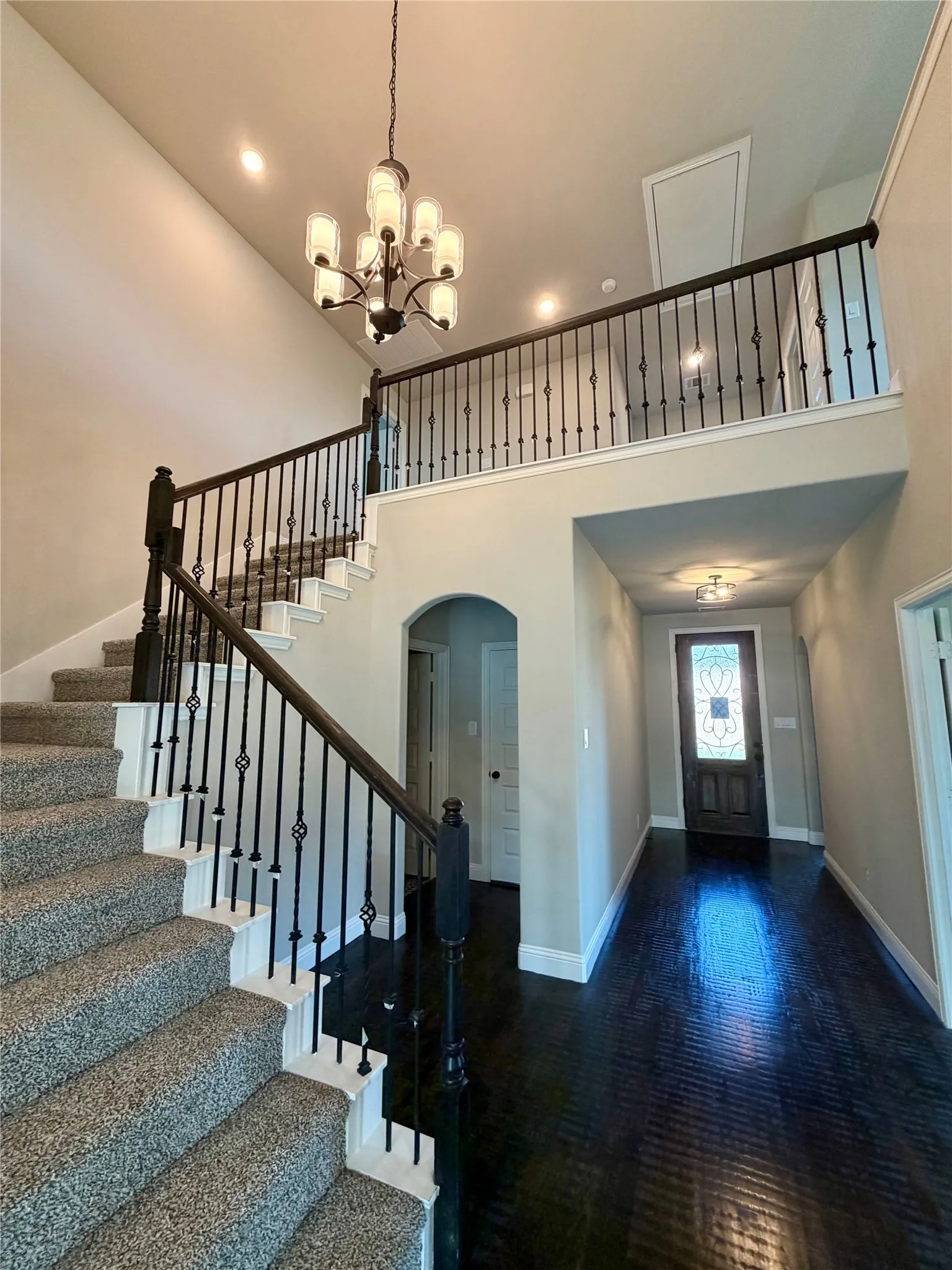 Impressive entry with Cathedral ceiling, Ebony hardwood floors, wrought iron spindles, and Mate Black chandelier