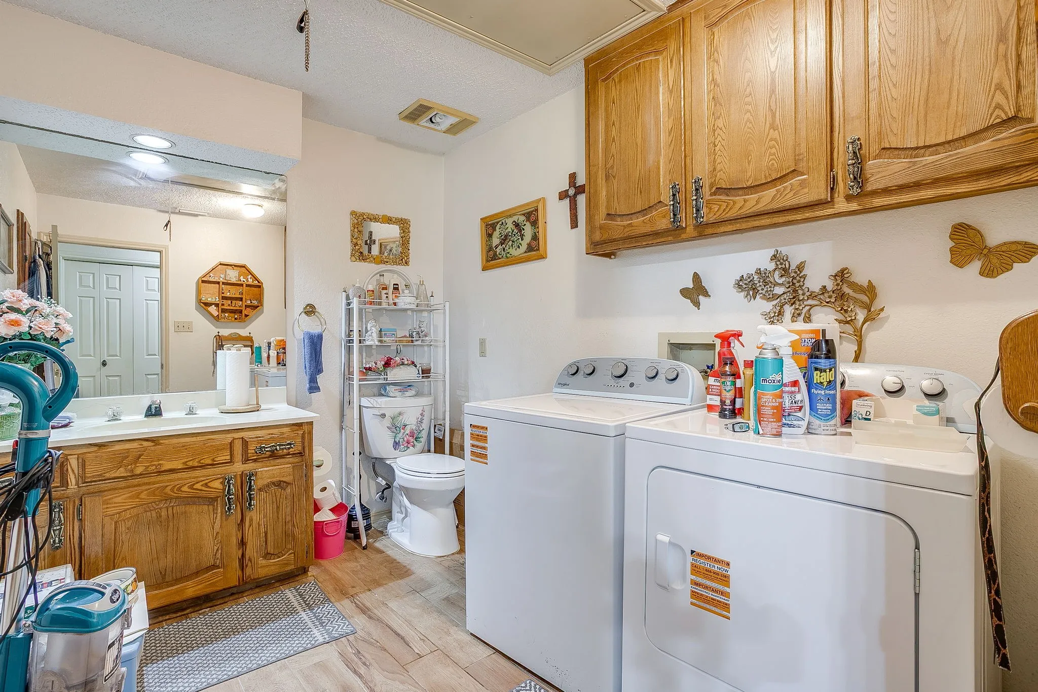 Wood-finish flooring, wood-finish cabinetry, built-in vanity with white countertop, recessed lighting, and a mirrored wall