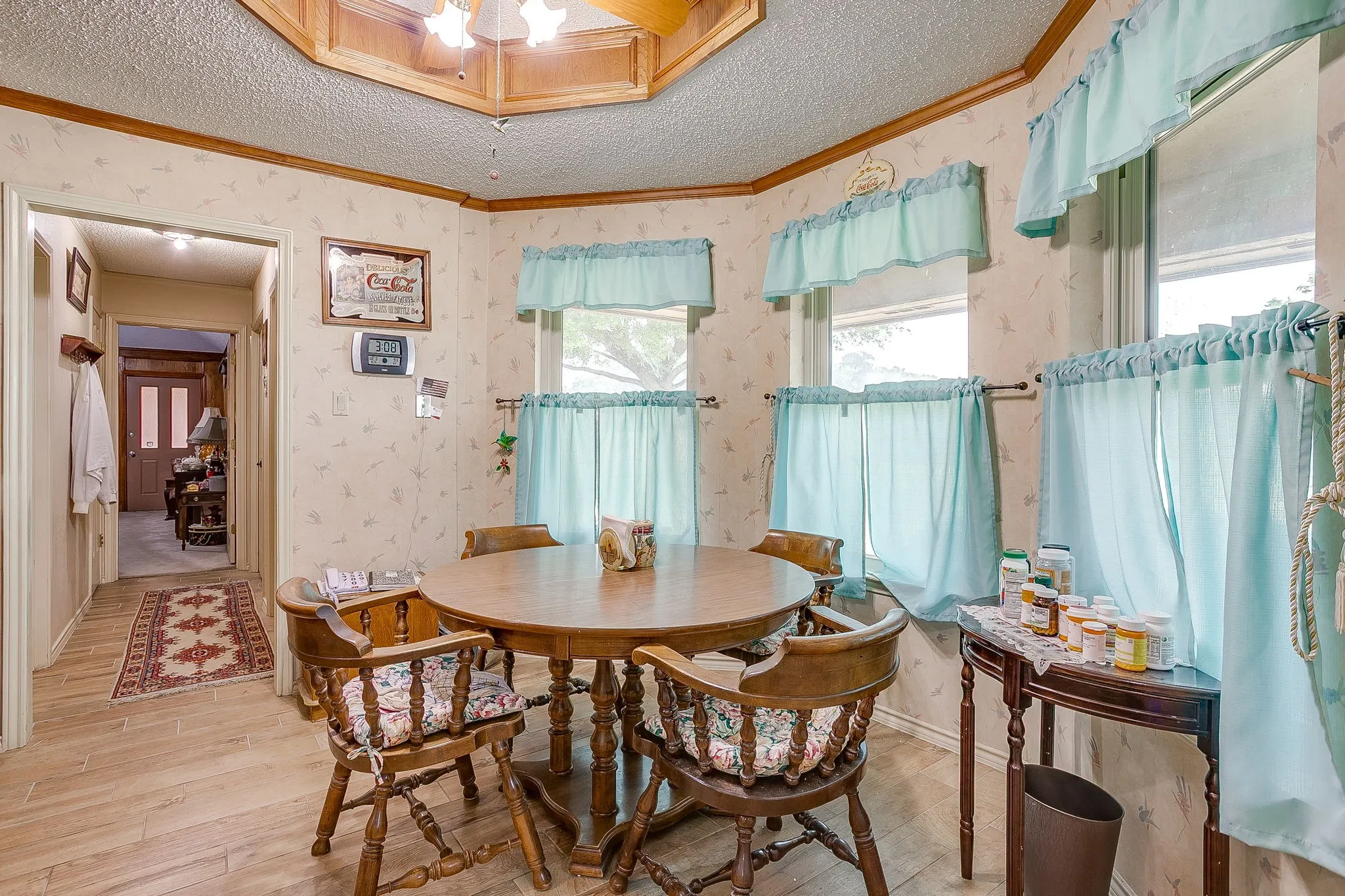 Wood-finish flooring with patterned wallpaper and multiple windows