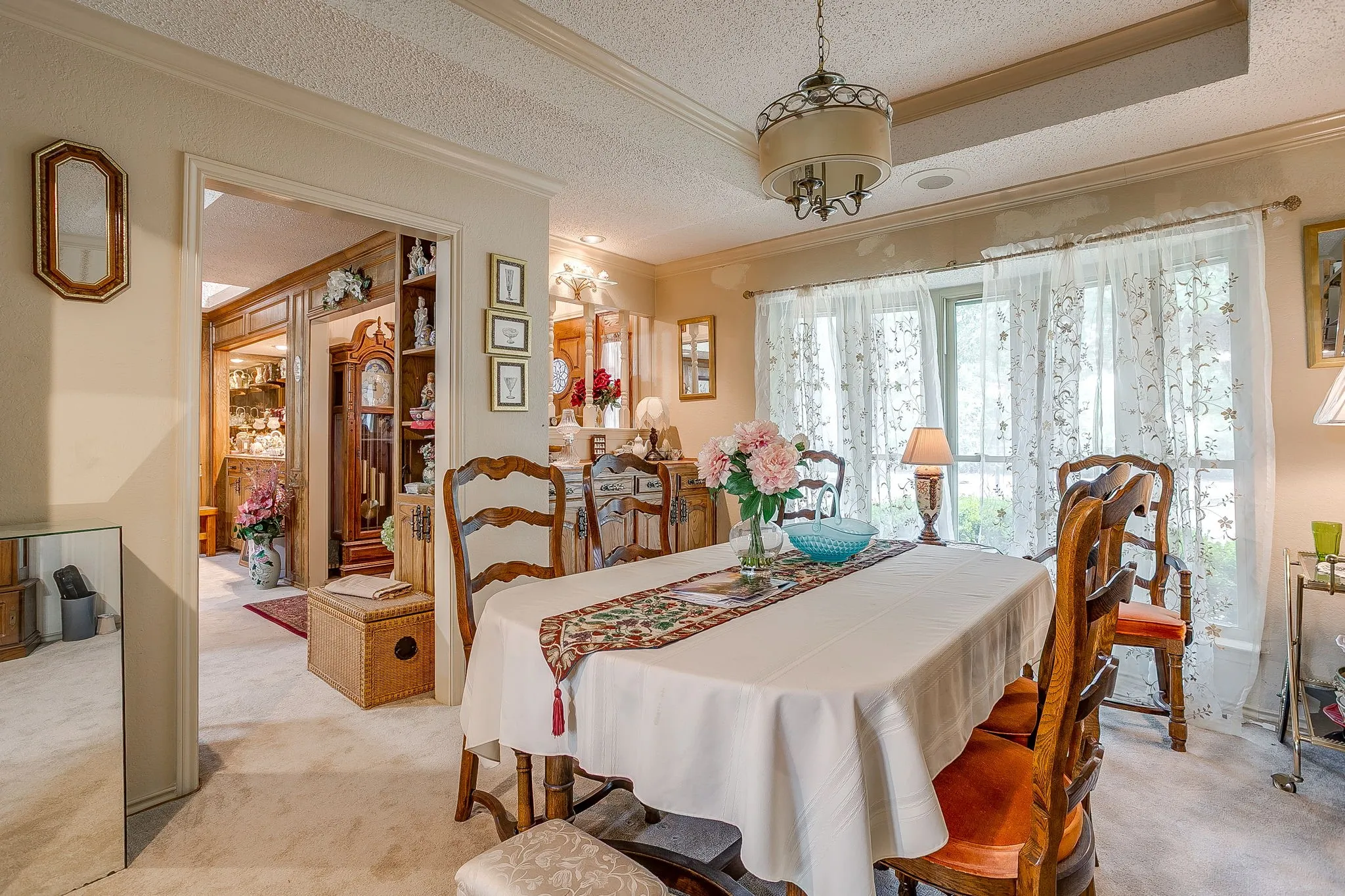 Room featuring a large window, a decorative ceiling fixture, and light-toned wall-to-wall carpeting