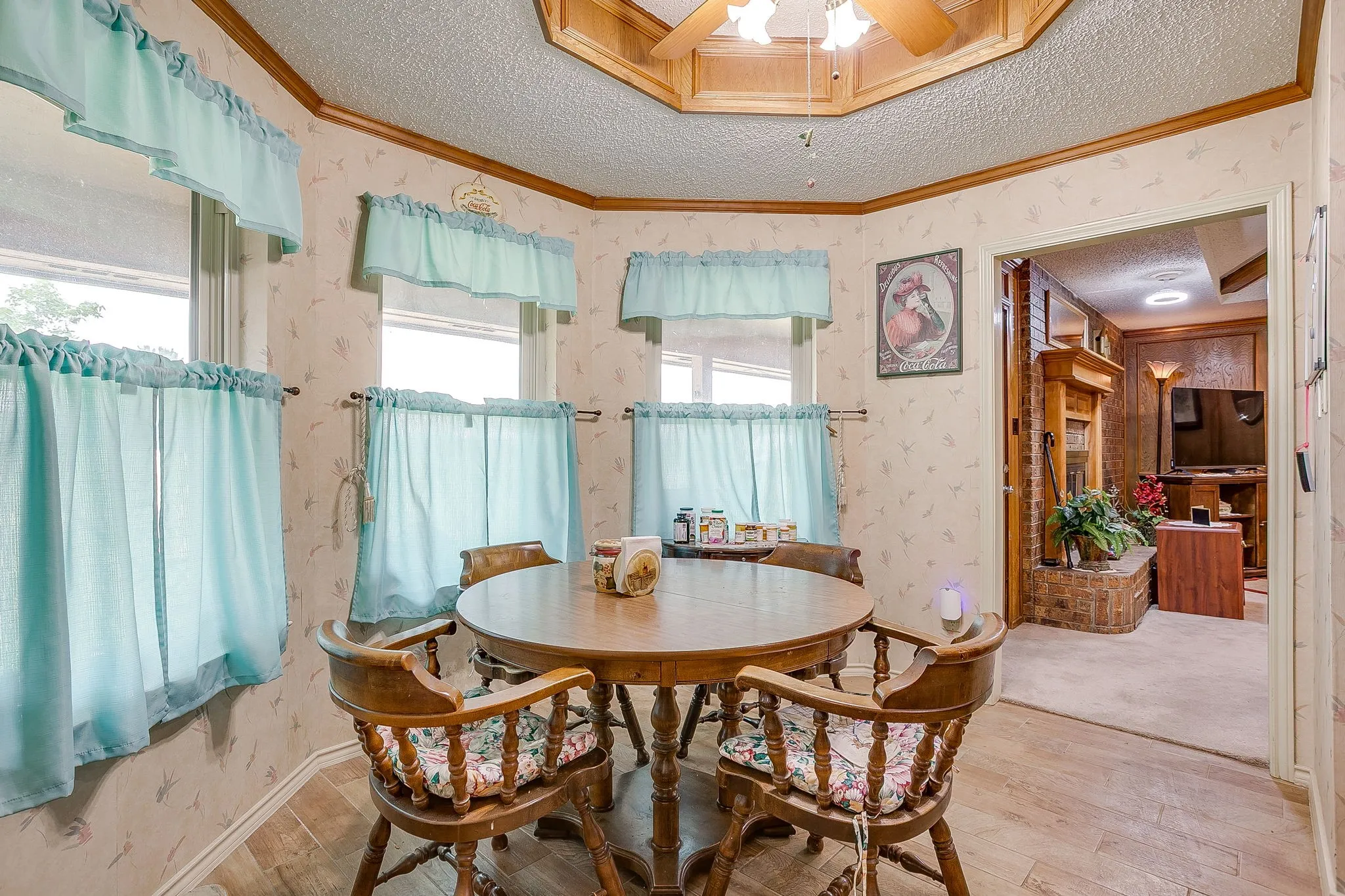 Bright dining area with multiple windows, wood-finish flooring, a wood-paneled ceiling, and a ceiling fan