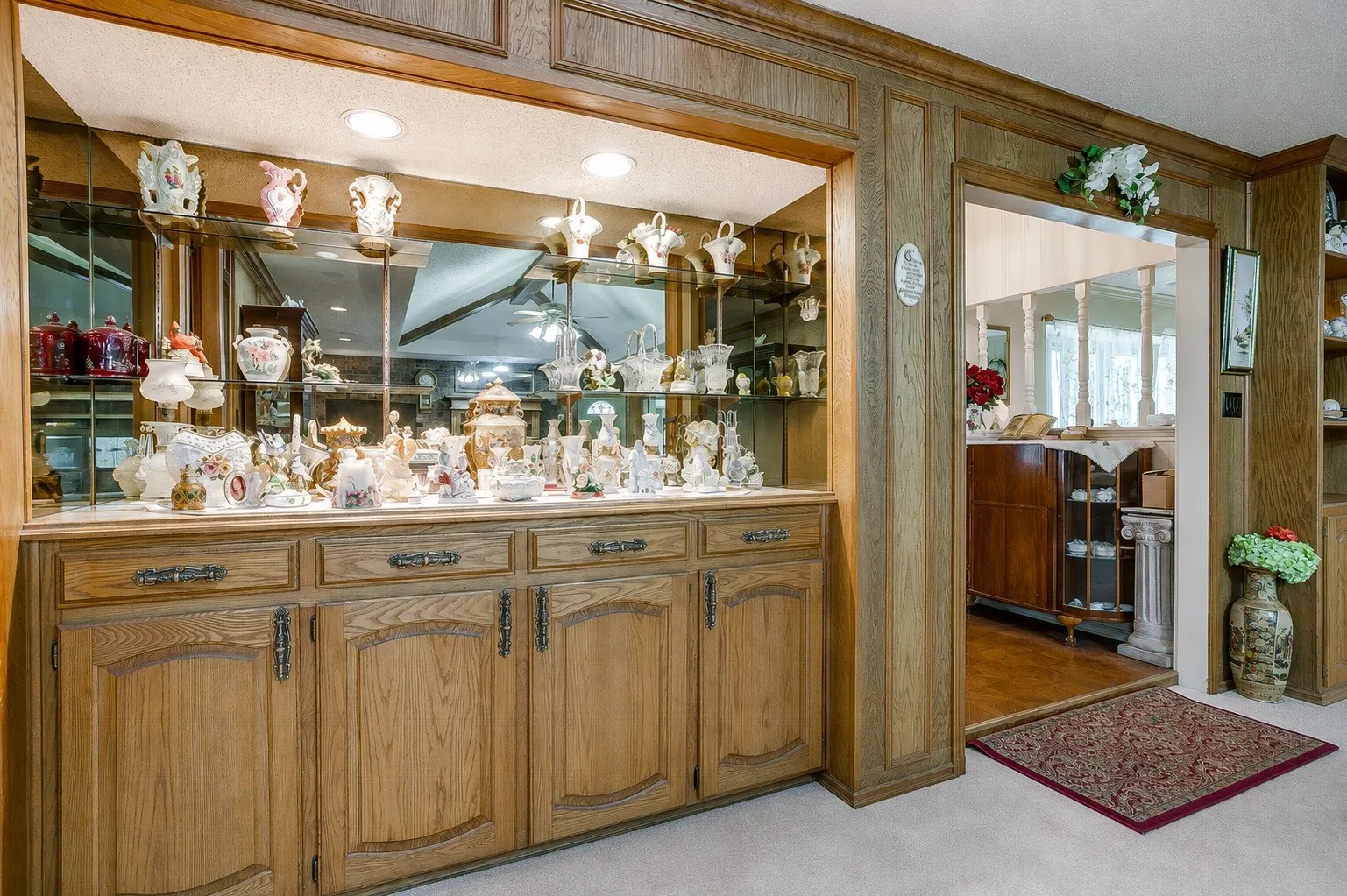 Built-in cabinetry with wood paneling, mirrored display shelving, and recessed lighting