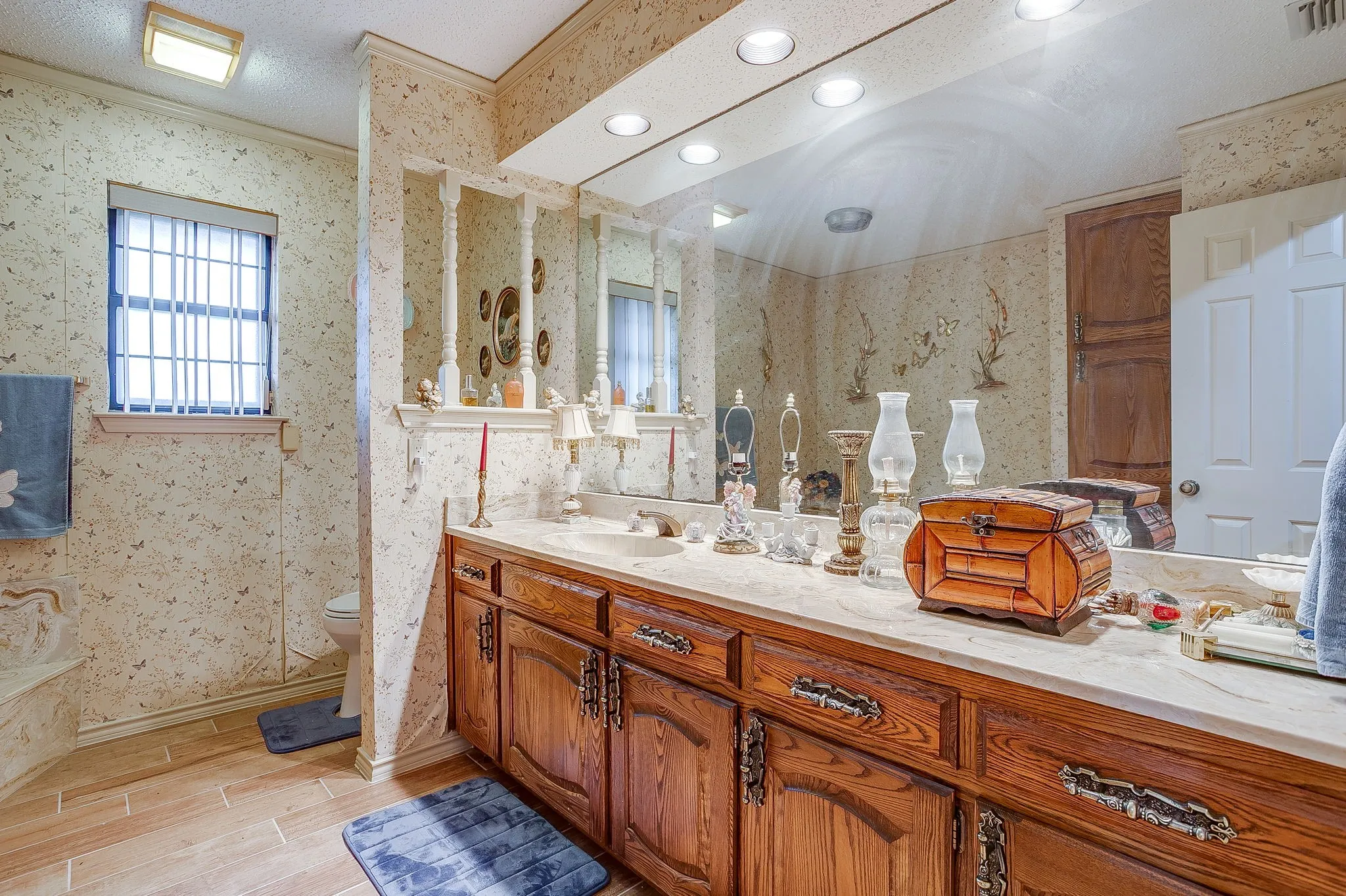 Double vanity with integrated sinks, wood-finish cabinetry, and full-wall mirrors