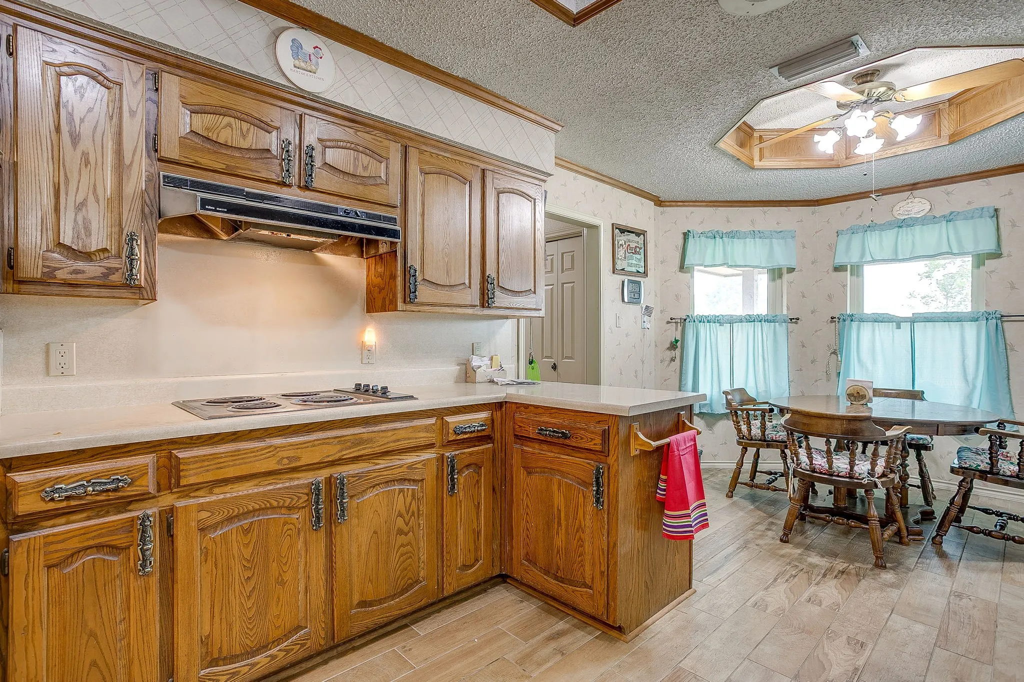 Wood-finish cabinetry with decorative hardware, solid surface countertops, and a built-in electric cooktop