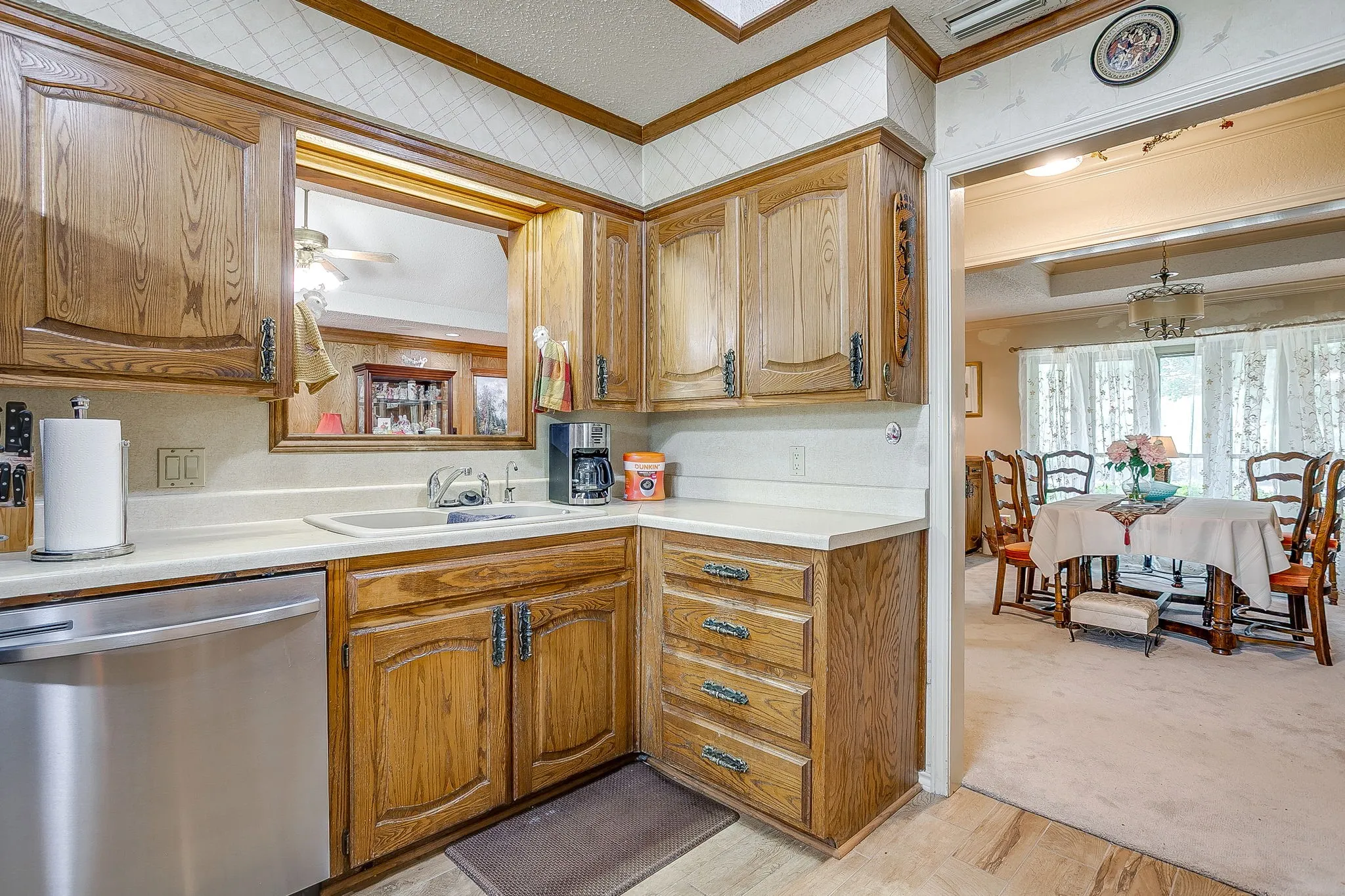 Wood cabinetry with decorative hardware, solid surface countertops, undermount sink, and stainless steel dishwasher