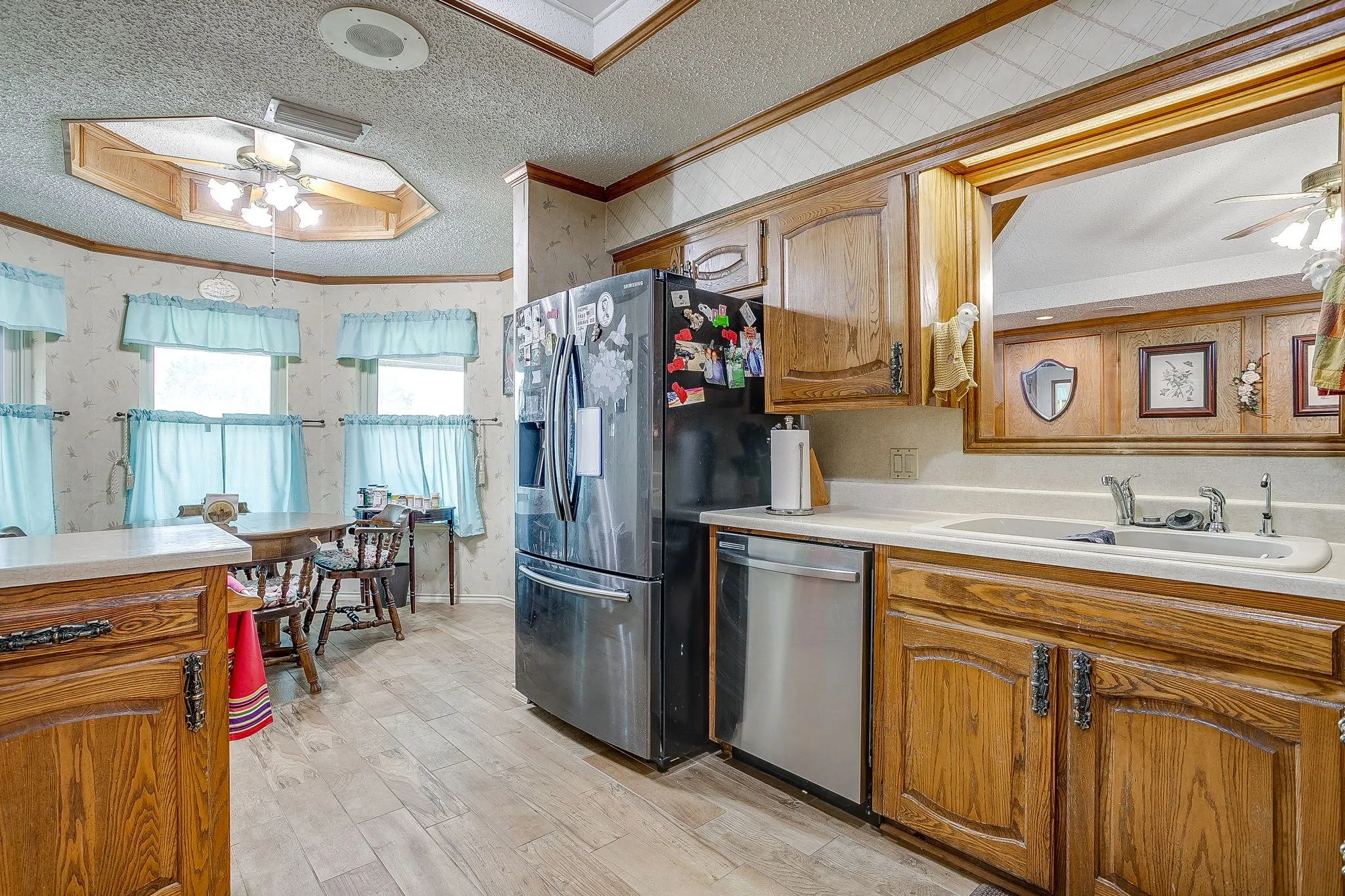Wood-finish flooring, wood cabinetry, and a built-in kitchen sink with a light-colored countertop