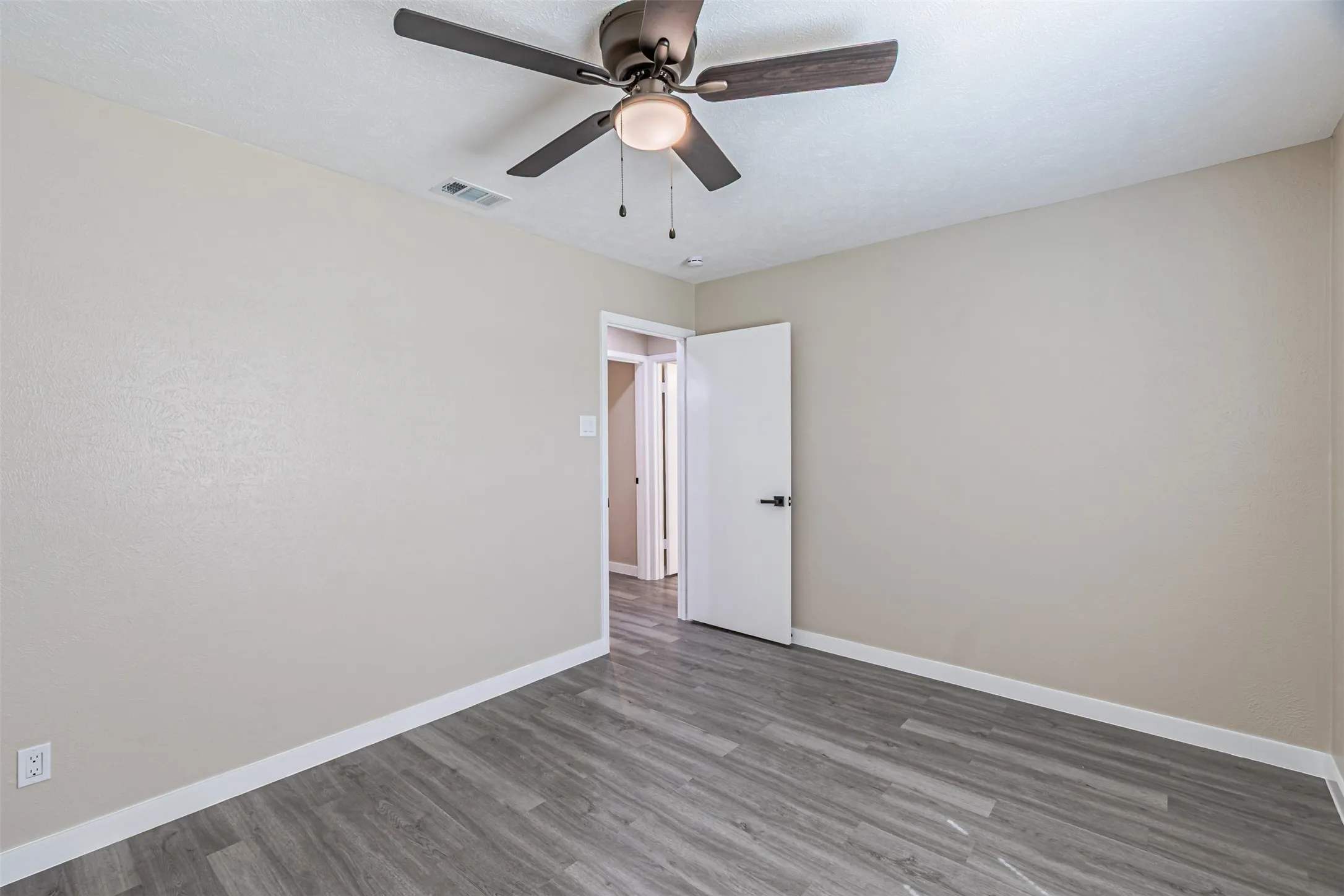 Room featuring wood-finish flooring, neutral wall paint, and a ceiling fan with integrated lighting