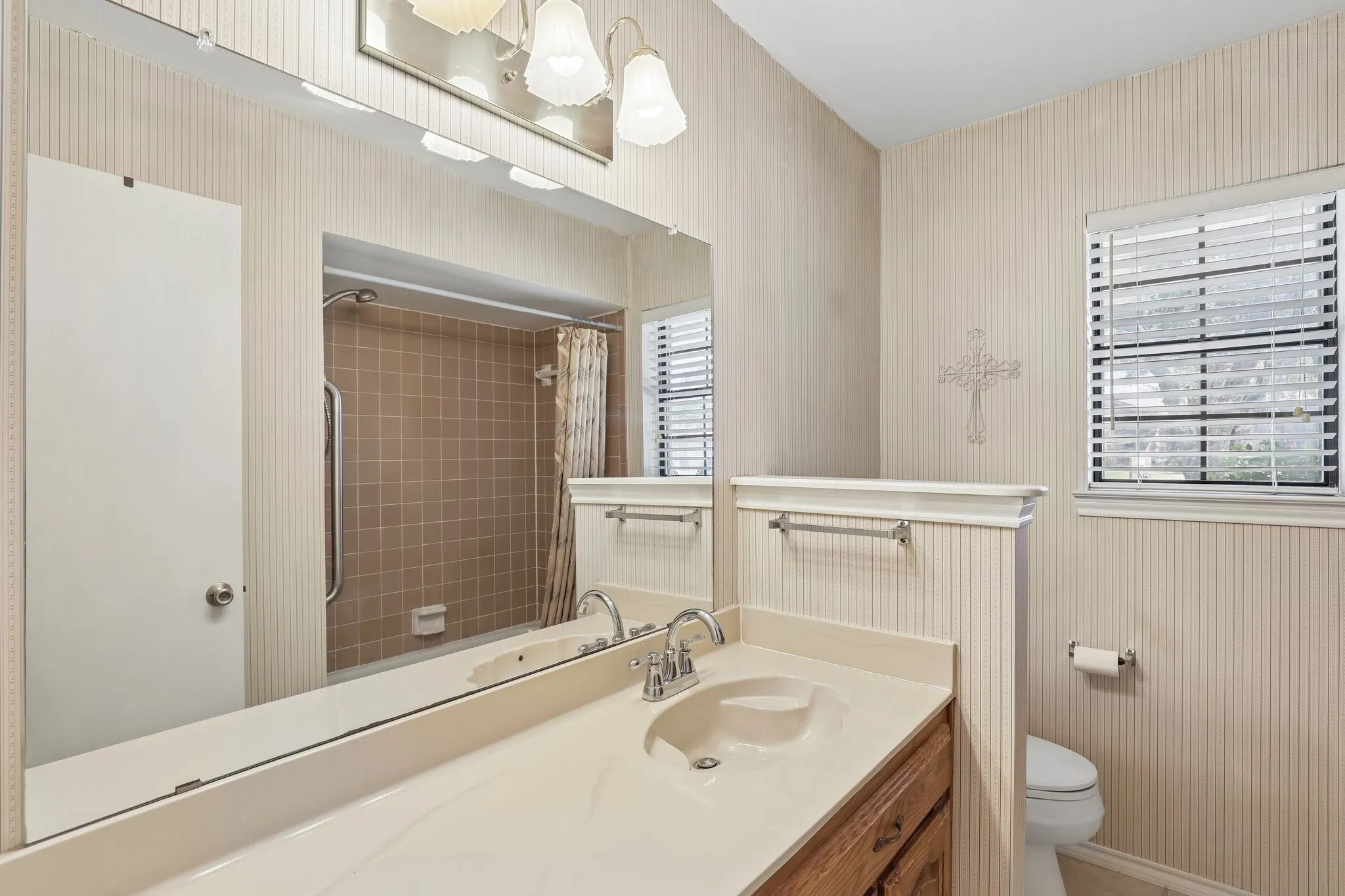 Vanity with integrated sink, wood-finish cabinetry, and polished chrome faucet