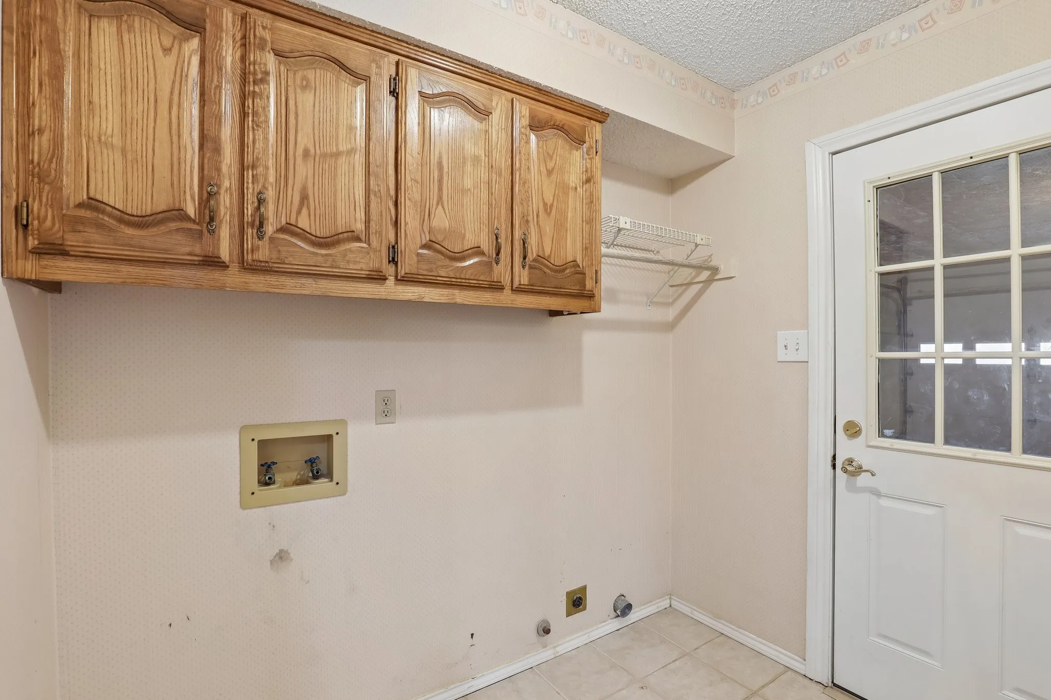 Wood-finish upper cabinetry, built-in wire shelving, and tiled flooring