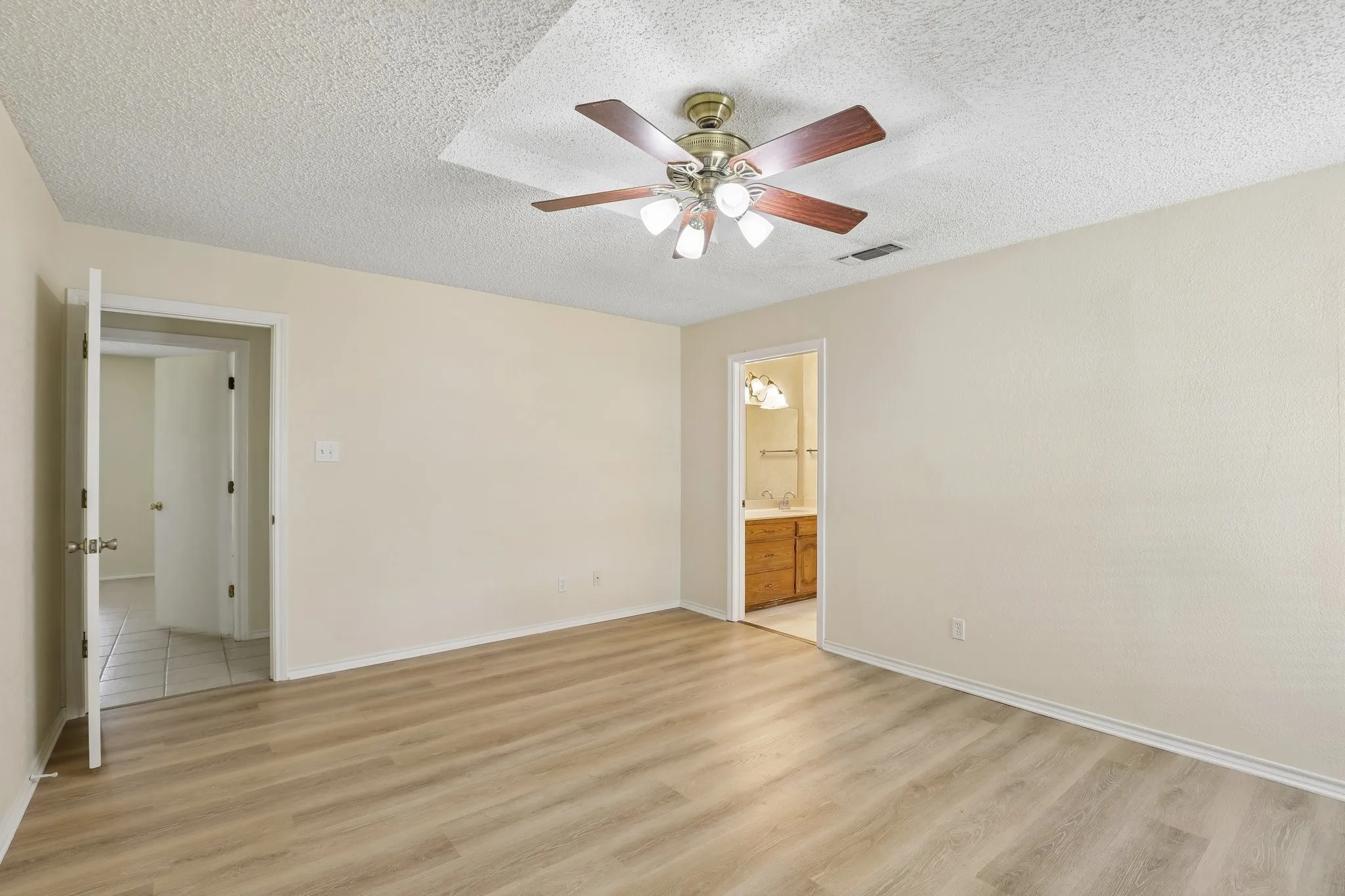 Vinal plank flooring throughout, ceiling fan with integrated lighting, and an overhead light tray feature