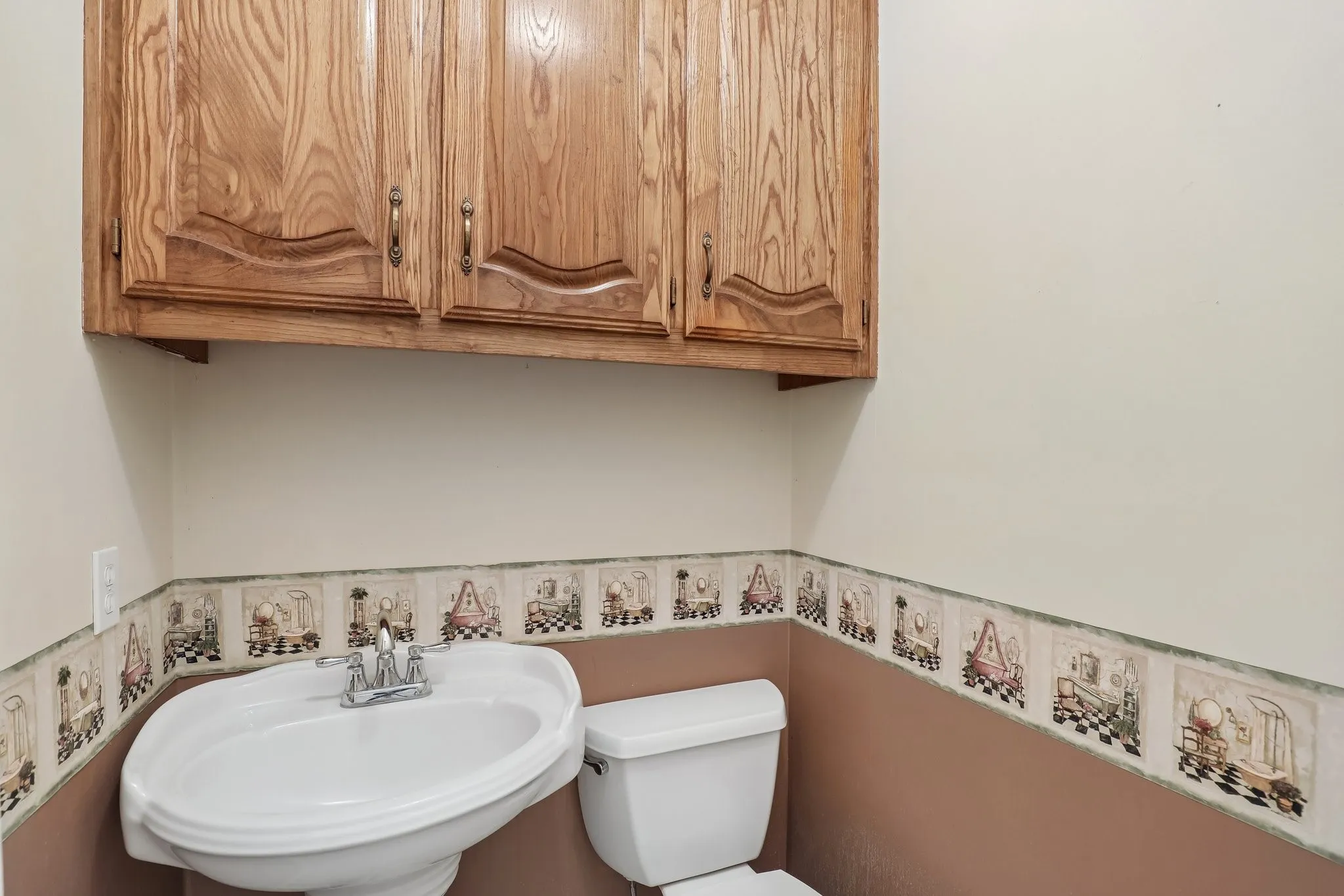 Wall-mounted wood cabinetry with hardware, pedestal sink with chrome faucet, and white toilet