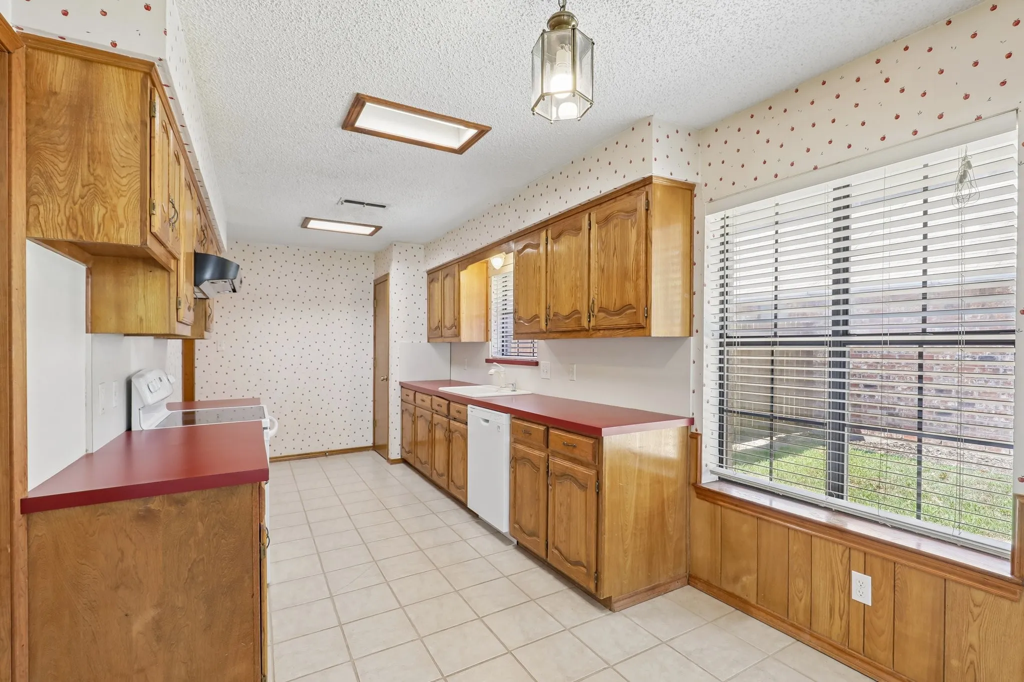 Kitchen featuring wood cabinetry, red countertops, tile flooring, and a large window