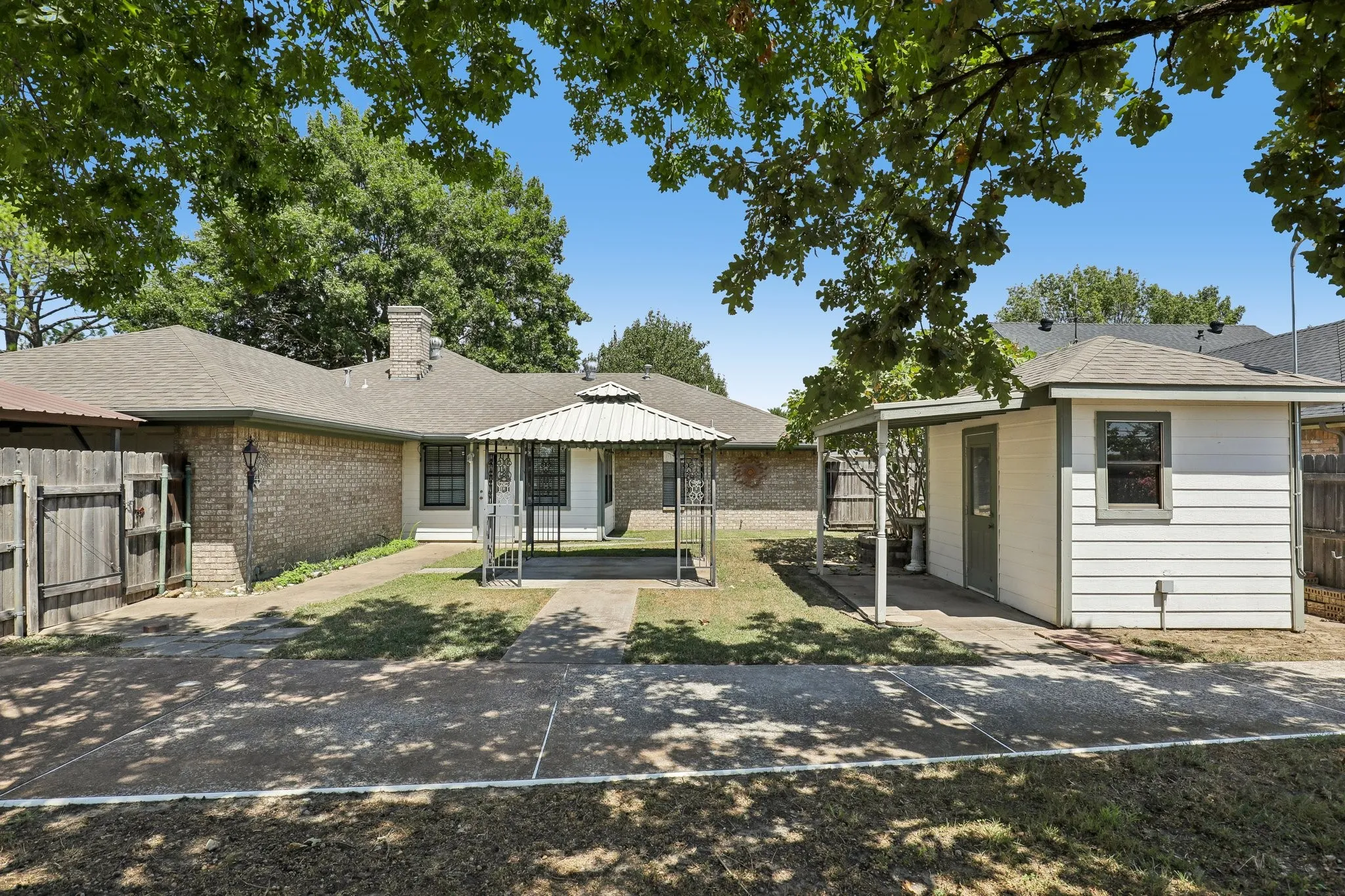 Brick exterior residence featuring a detached outbuilding, a gondola and a wooden privacy fence.