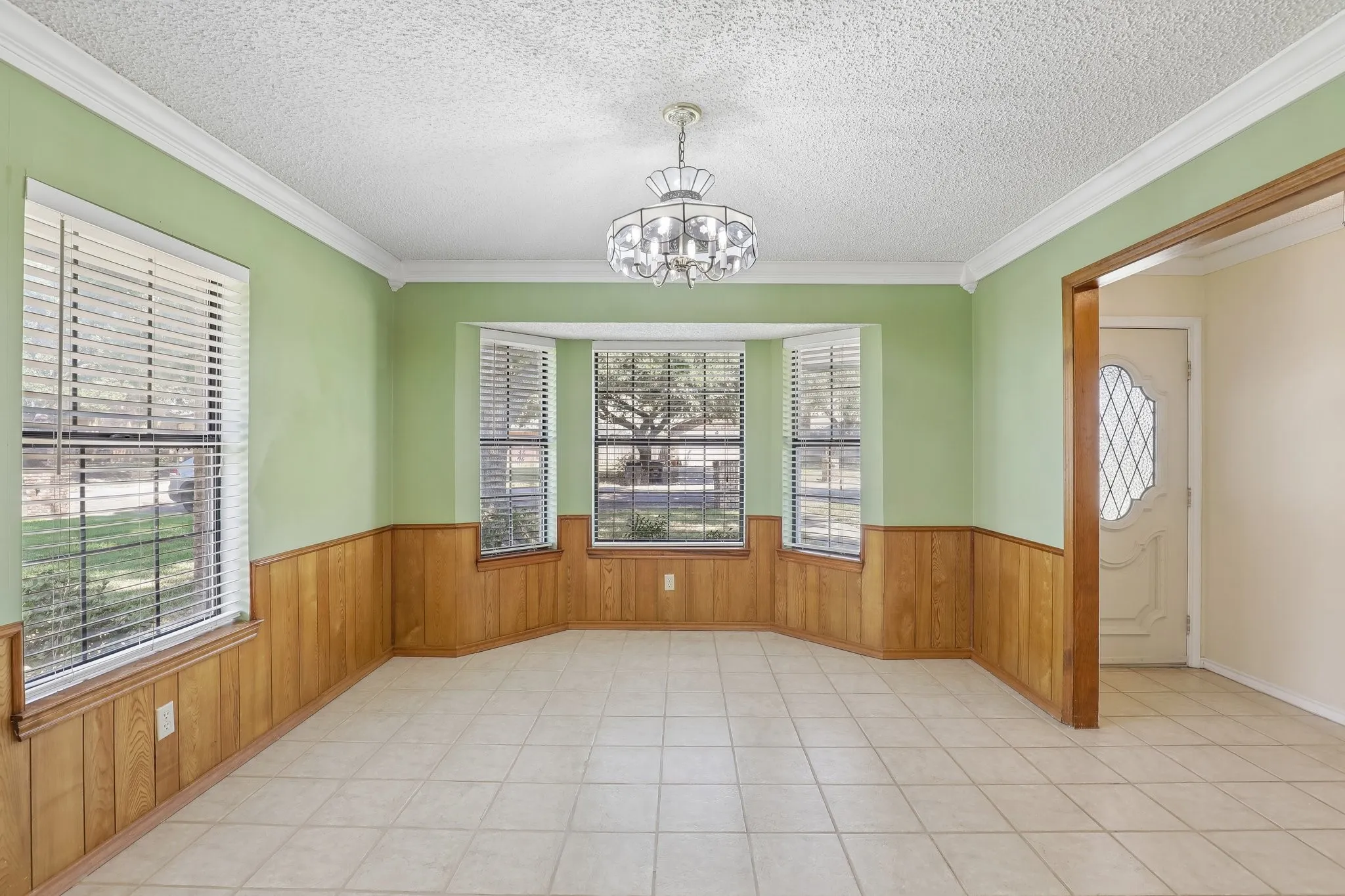 Bay window, tile flooring, wood paneling, decorative chandelier, crown molding