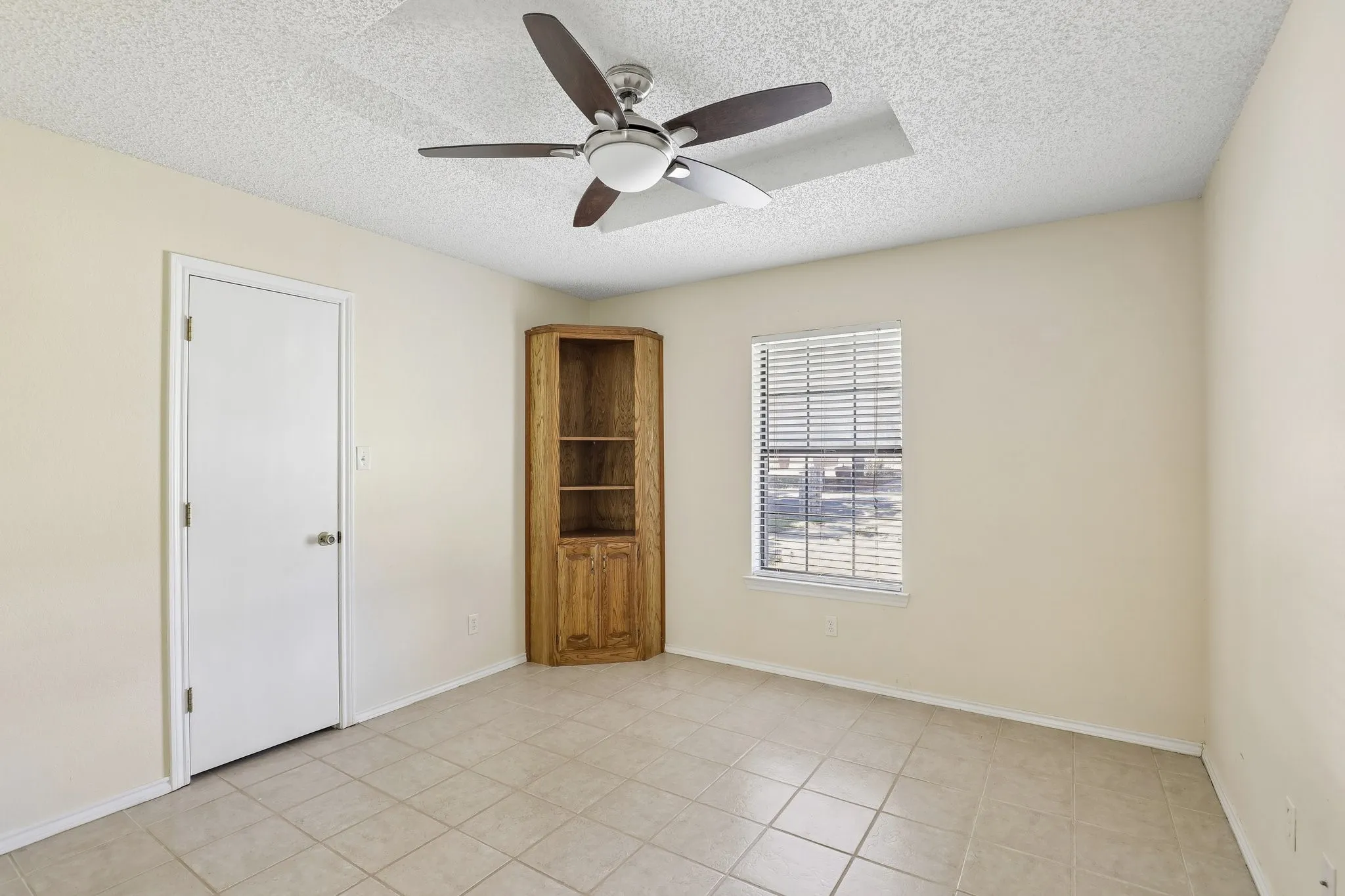 Featuring wooden built-in corner cabinet and ceiling fan