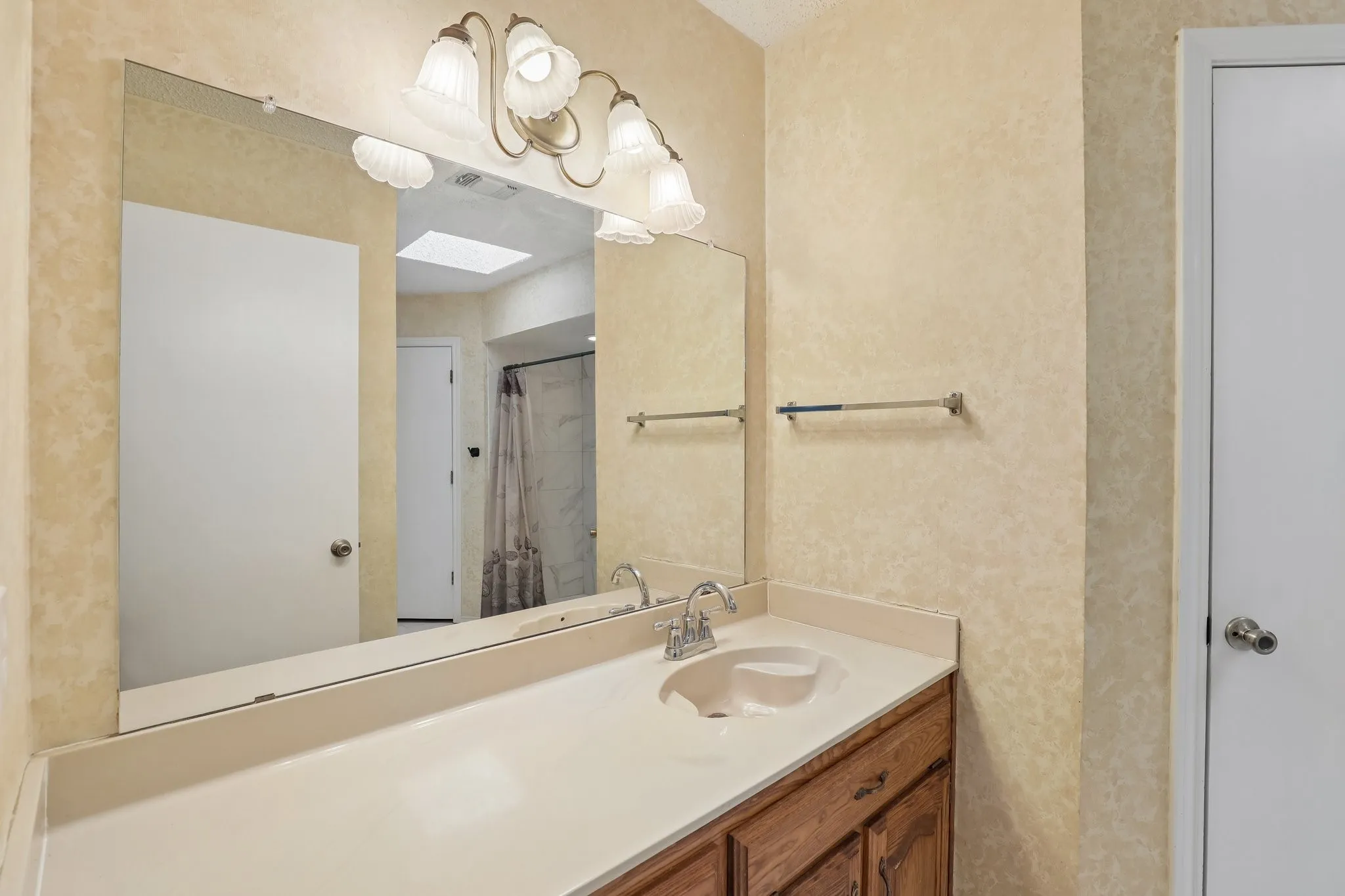 Vanity with integrated sink, wood-finish cabinetry, and wall-mounted light fixture