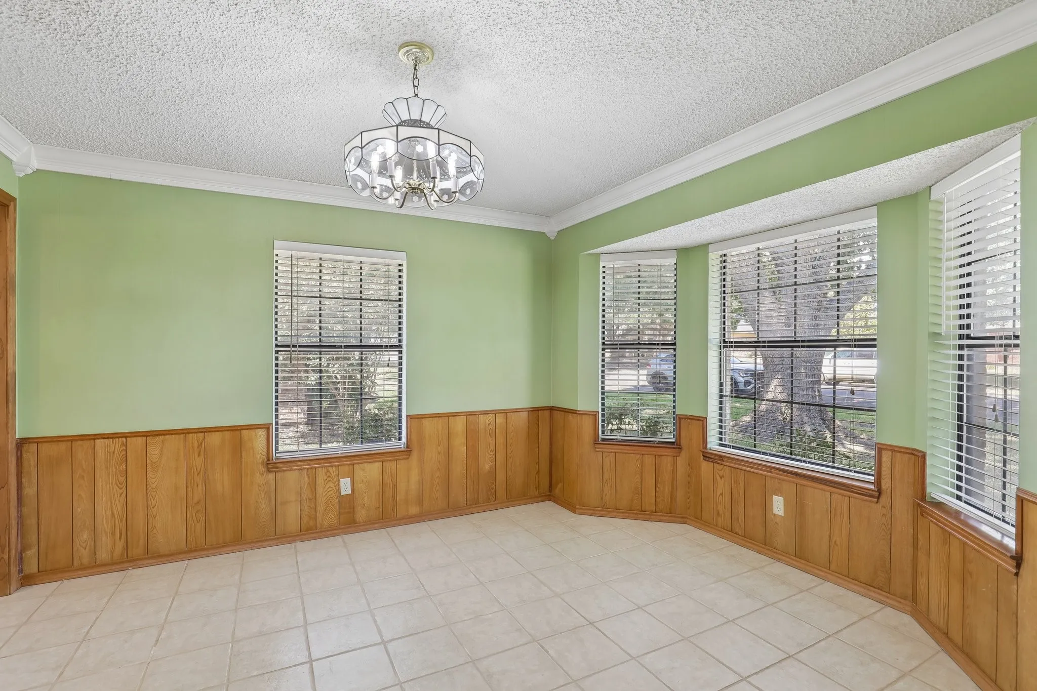 Bay window, tile flooring, wood paneling, decorative chandelier, crown molding