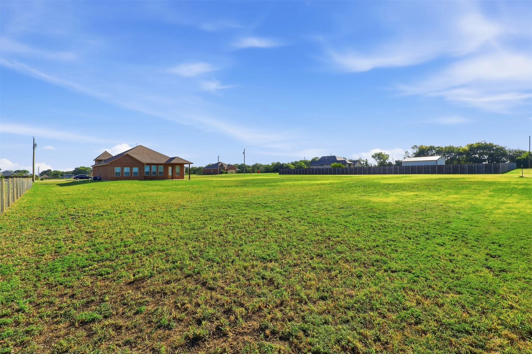 Expansive grassy lot with a wood fence bordering the property