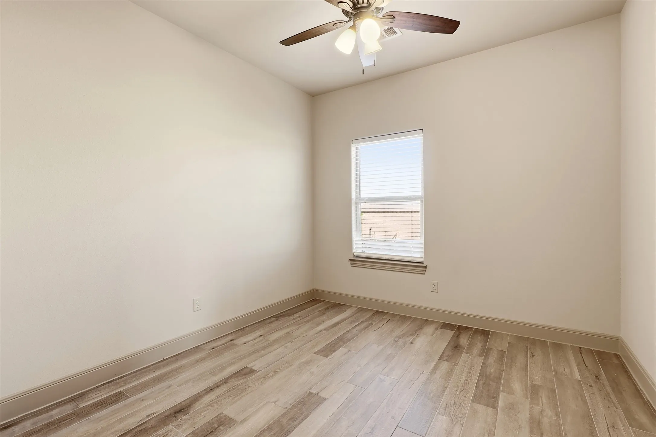 Wood-finish flooring, single window with blinds, ceiling fan with integrated lighting, neutral wall tones