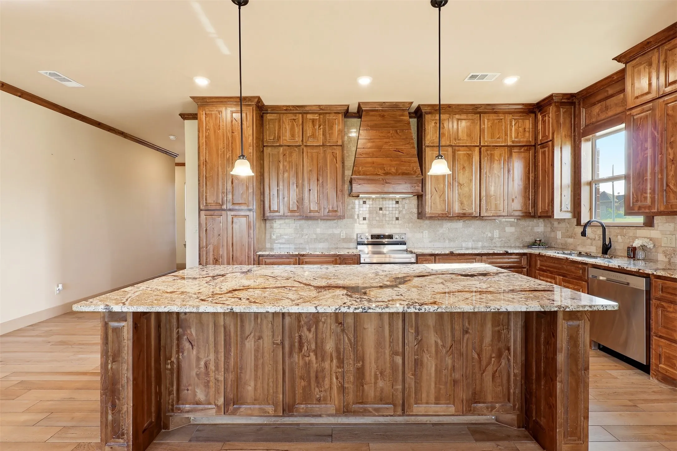 Kitchen featuring wood-finish cabinetry, stone countertops, stainless steel appliances, and a tiled backsplash