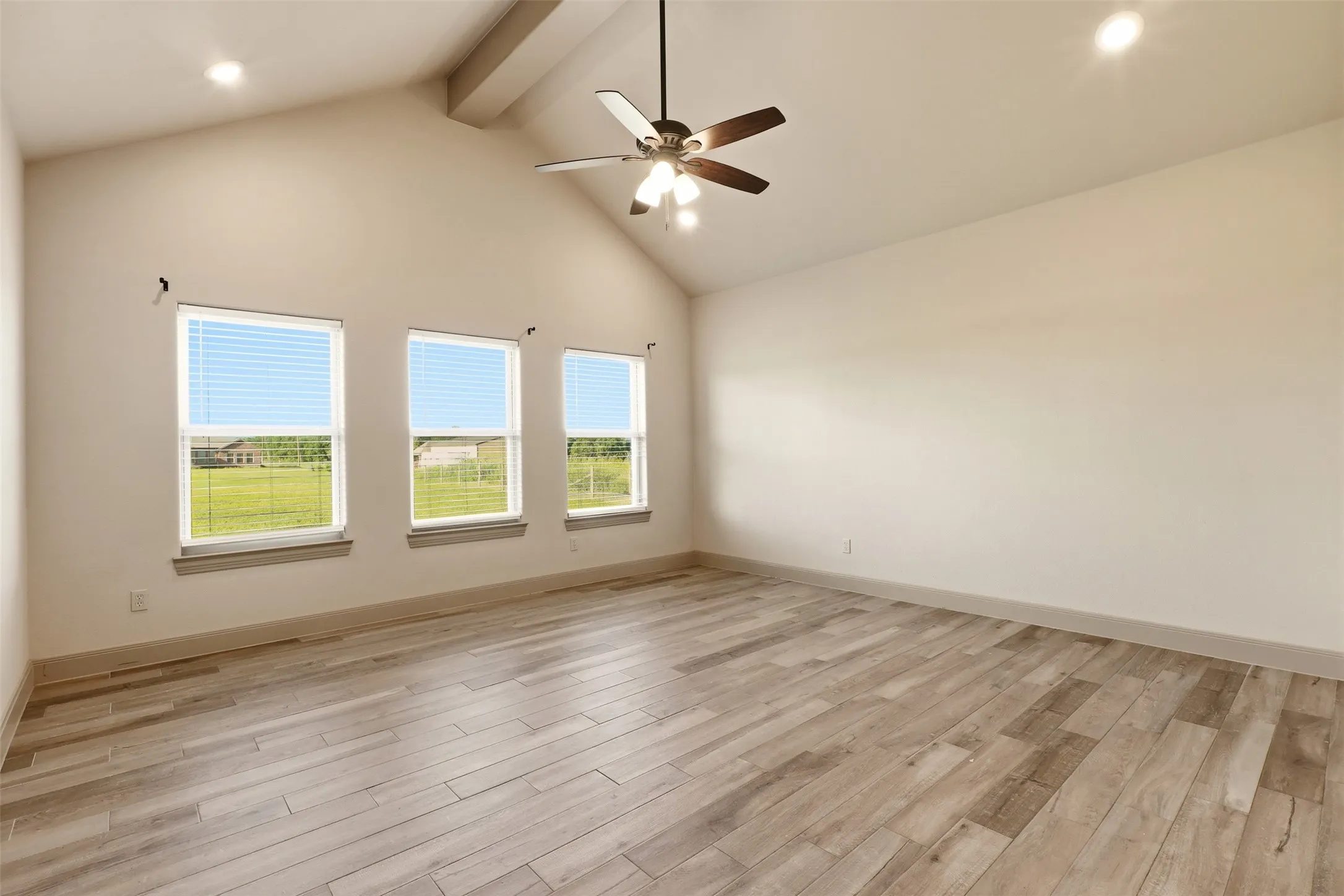 Vaulted ceiling with an exposed beam, recessed lighting, and a ceiling fan