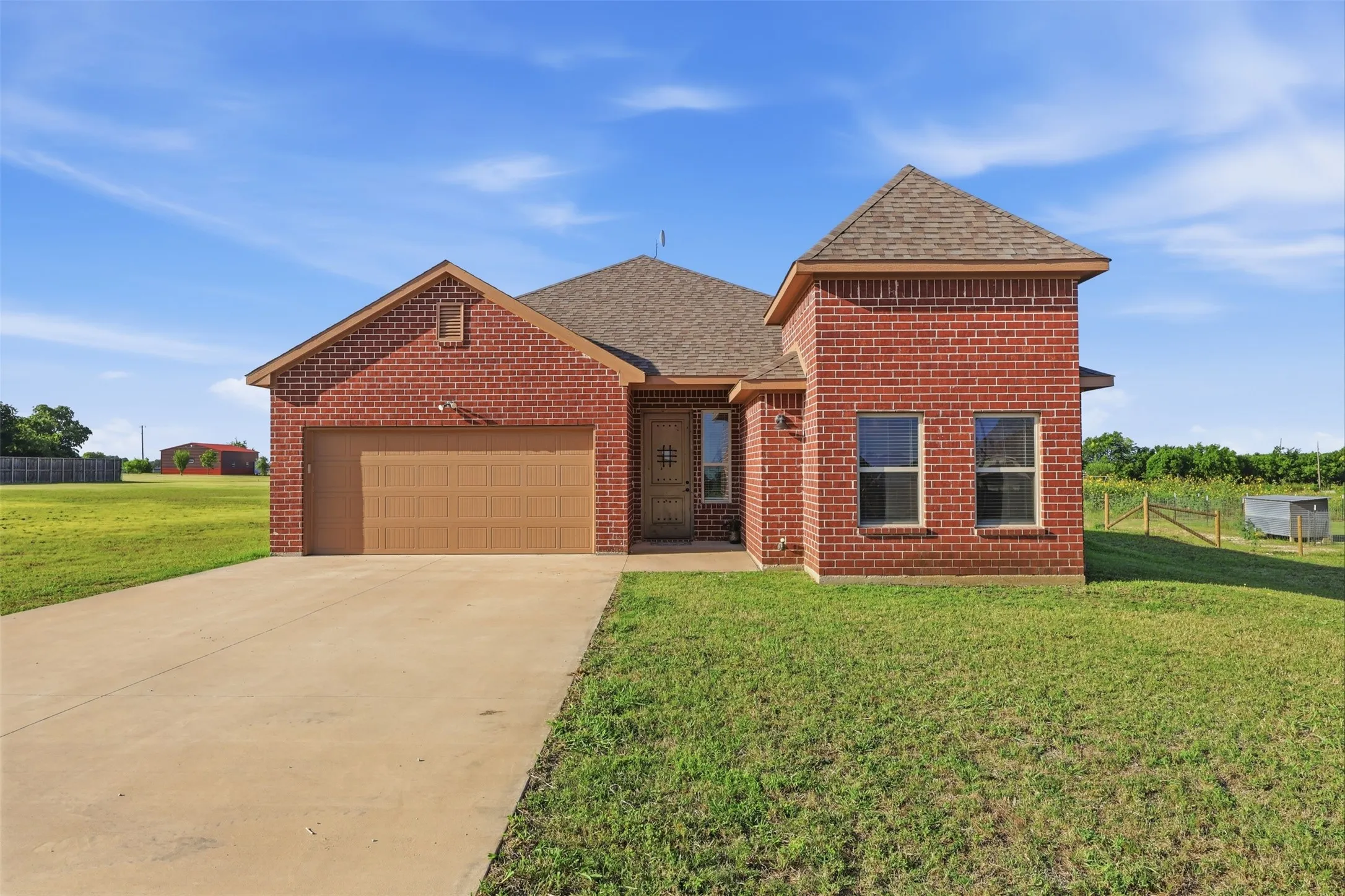 Red brick exterior with a distinctive turret feature, attached garage with a concrete driveway, and a shingled roof
