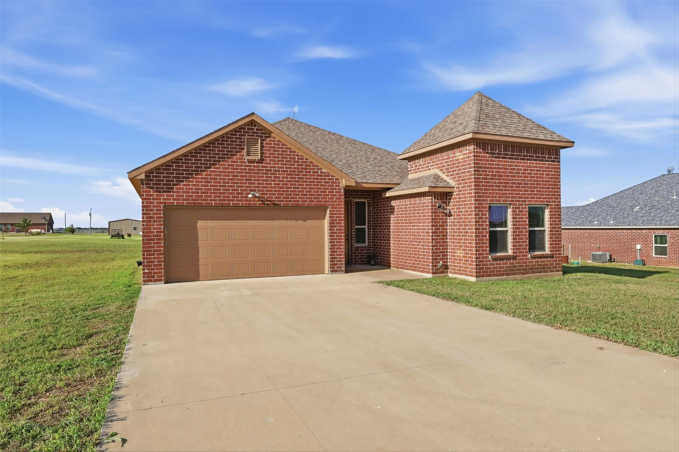 Brick exterior featuring a hip roof, two-car garage, and concrete driveway