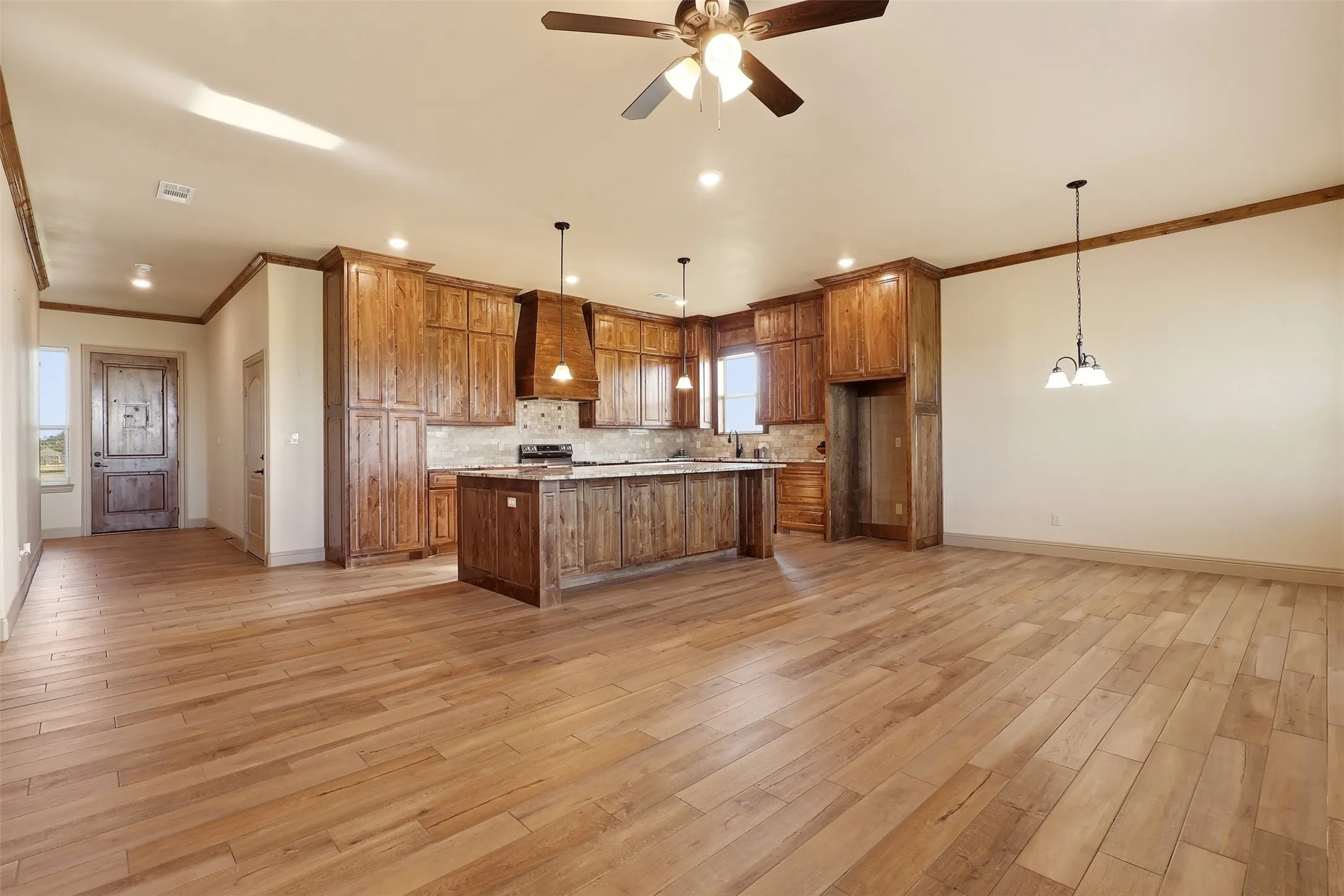 Open-concept living area with wood-finish flooring, recessed lighting, ceiling fan, and wooden cabinetry