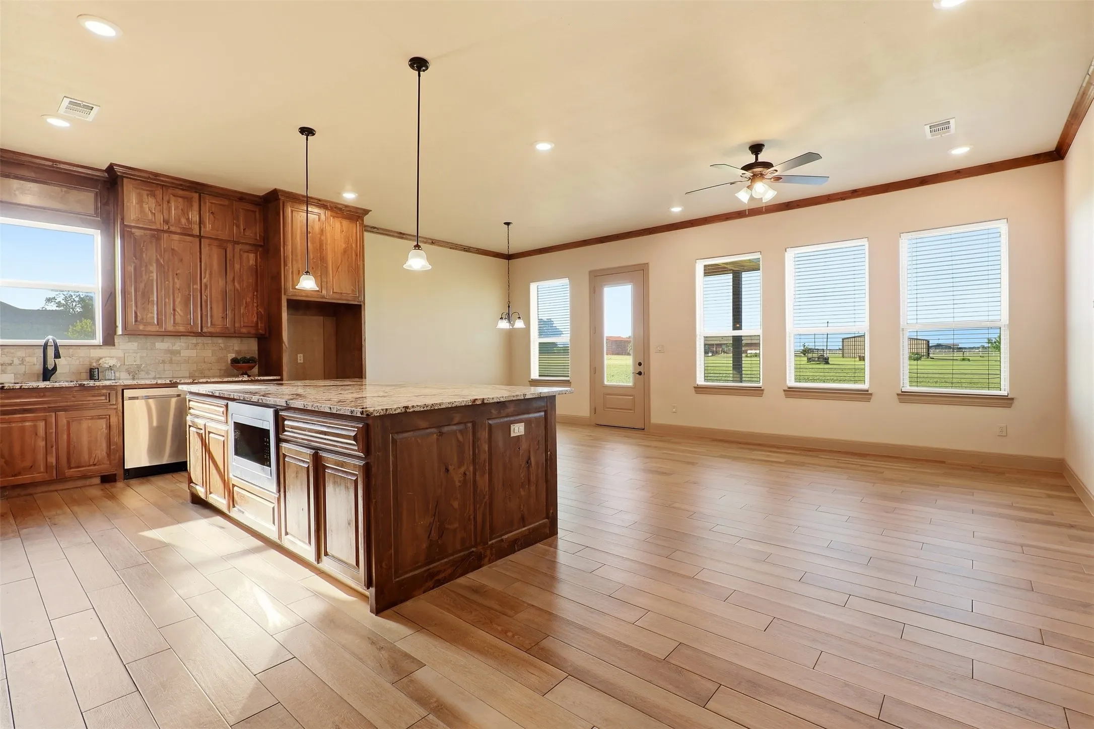 Spacious kitchen featuring a large island, wood-finish cabinetry, built-in microwave, and tile backsplash