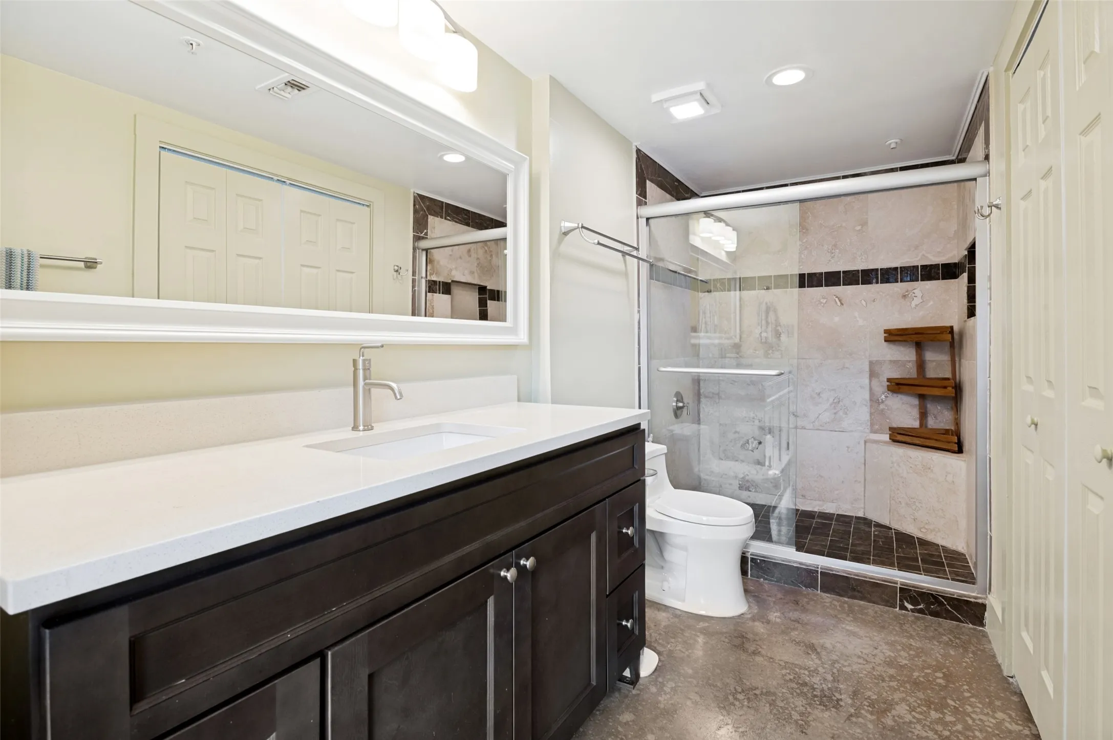 En-suite bathroom with dark wood-finish vanity with a white countertop and undermount sink