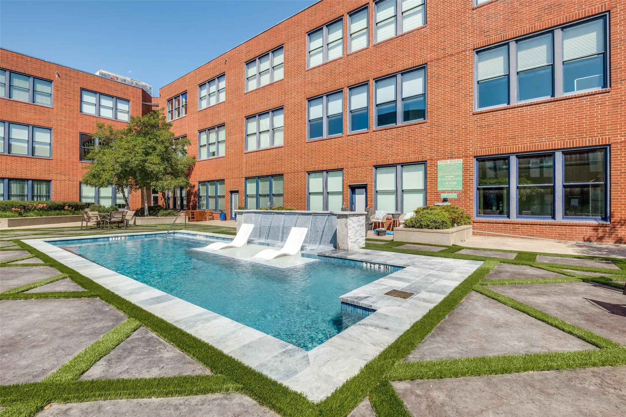 Courtyard pool with water feature, integrated lounge seating, and stone coping